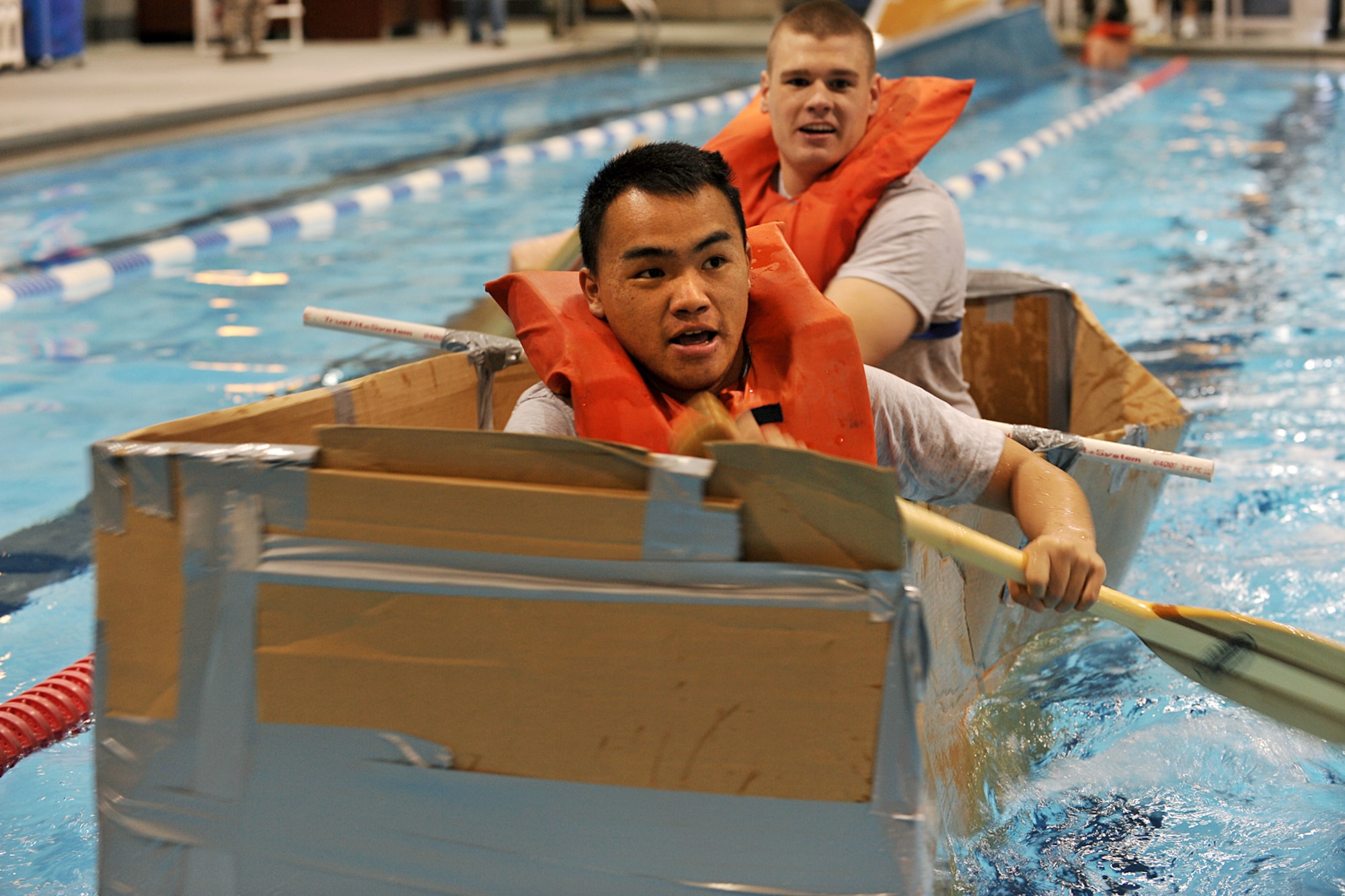 OFFUTT AIR FORCE BASE, Neb. - Airmen 1st Class Tony Vang and Scott Rushton, both members of the 55th Strategic Communications Squadron, paddle across the pool in the Offutt Field House during the cardboard boat race Oct. 16. Team Offutt participated in various Wingman Day activities, including the carboard boat race, to enhance their teamwork while having fun at the same time.  U.S. Air Force photo by Charles Haymond