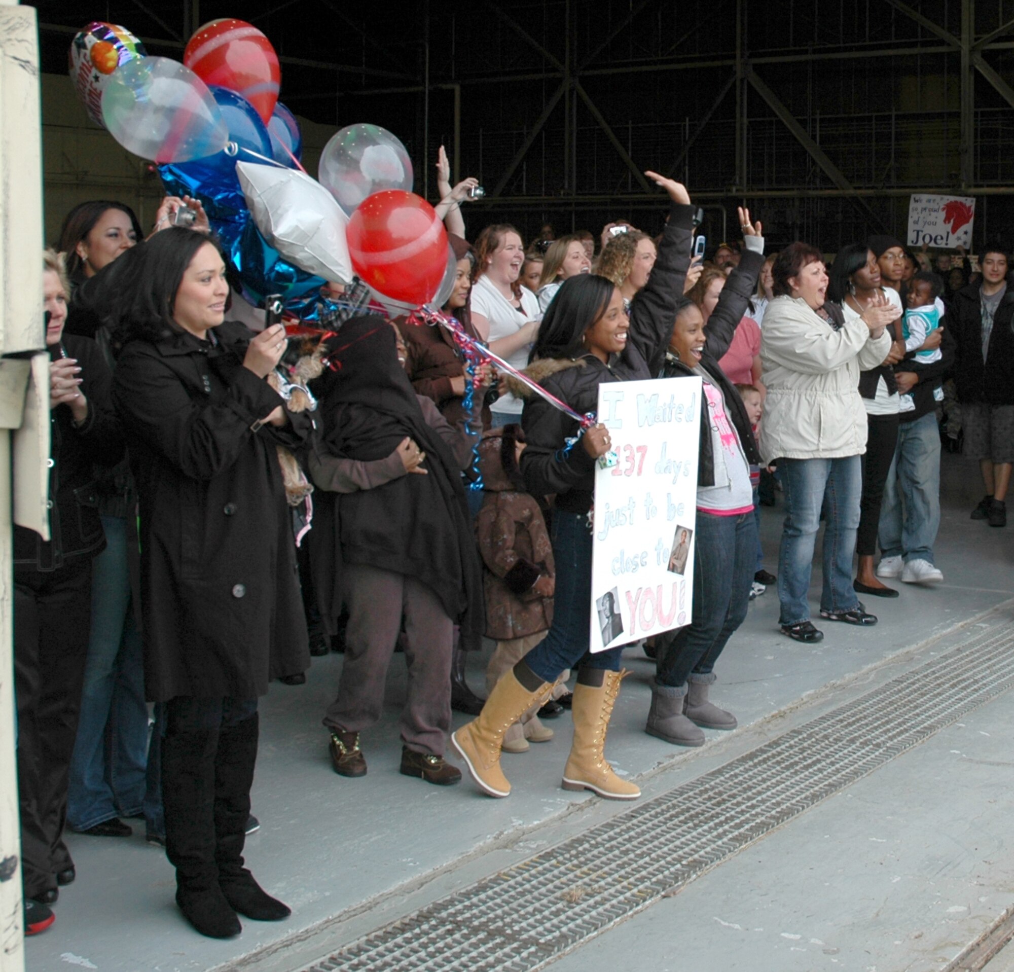 Friends and family members of returning 819th RED HORSE Squadron Airmen cheer as buses arrive at building 1460 Oct. 11. The nearly 250 Airmen are returning from a six-month deployment in support of operations in Iraq and Afghanistan. (U.S. Air Force photo/Senior Airman Dillon White)