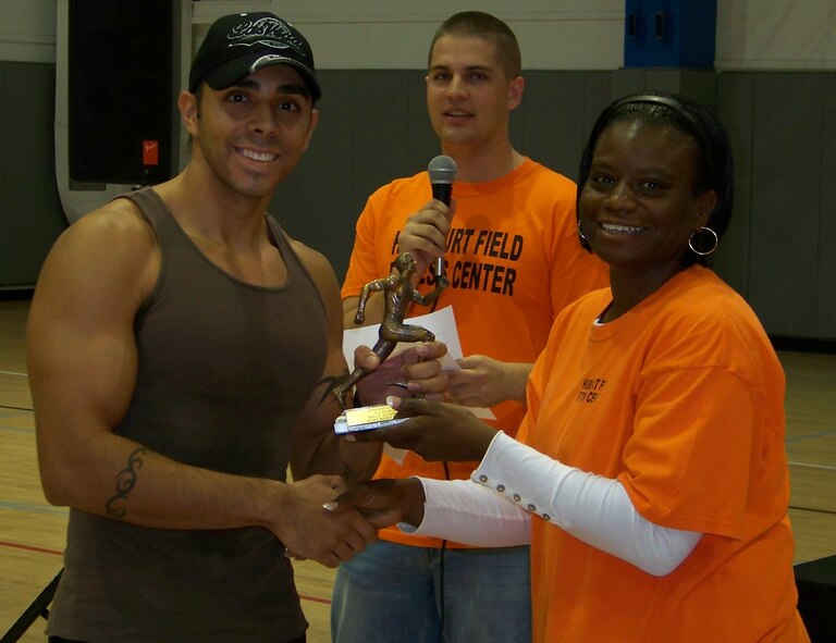 Master Sgt. Montrealle Parker, 1st Special Operations Force Support Squadron, right, and Senior Airman Alexander Wolchick, 1st SOFSS, center, present a trophy for the best male runtime to Staff Sgt. Anthony Cardenas, 1st Special Operations Comptroller Squadron, left, at the 5k Commando Run at the Aderholt Fitness Center at Hurlburt Field Oct. 17. Sergeant Cardenas said he trained hard for his first 5k run and finished in 18:41. (Air Force photo by Airman 1st Class Joe McFadden)