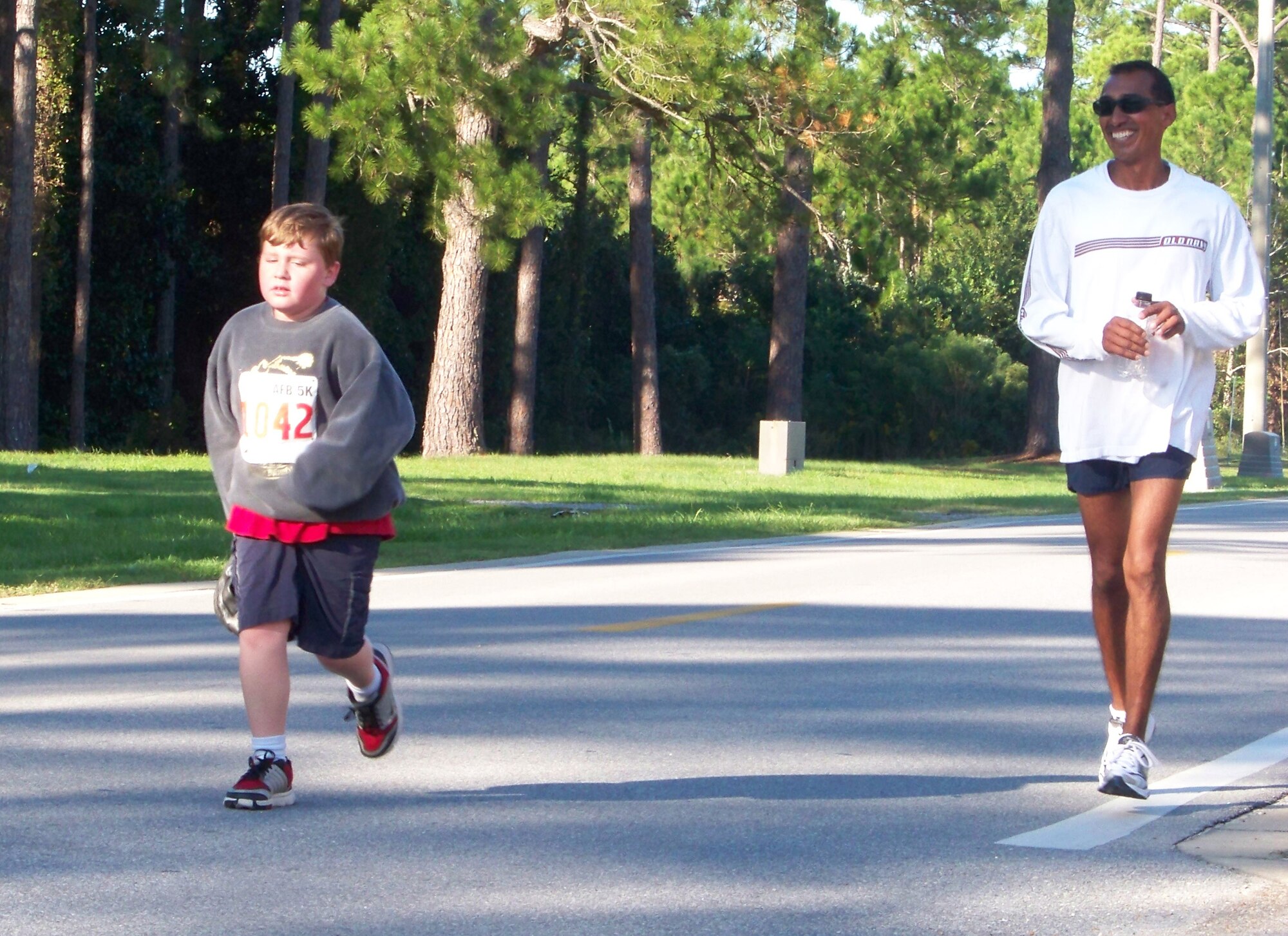 Nicholas Bridge, left, runs his last mile as Frank McNally, 1st Special Operations Component Maintenance Squadron, encourages him at the 5k Commando Run at the Aderholt Fitness Center at Hurlburt Field Oct. 17.   Both Mr. Bridge and Mr. McNally took 1st place for participants in their respective age groups. (Air Force photo by Airman 1st Class Joe McFadden.)