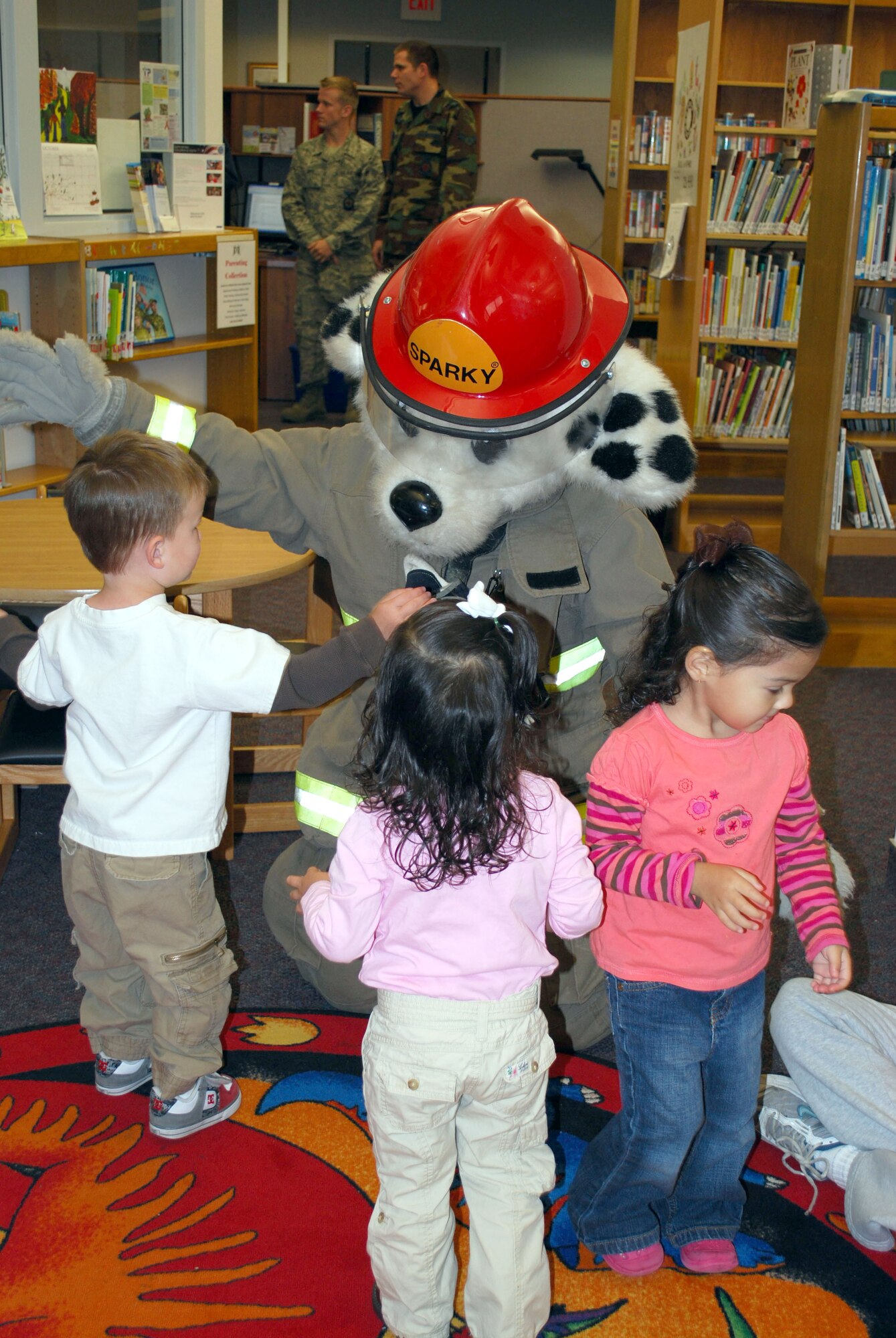 Sparky The Fire Dog gives a hug to Nolan, 2, while Lucy, 2, and Gabby, 3, wait their turn at the base library Oct. 6. Sparky was the special guest during story time which featured fire safety and prevention stories. National Fire Prevent Week Oct. 4 to 9 and this year's theme is "Stay Fire Smart! Don't Get Burned!"  (U.S. Air Force photo/Staff Sgt. Eydie Sakura)