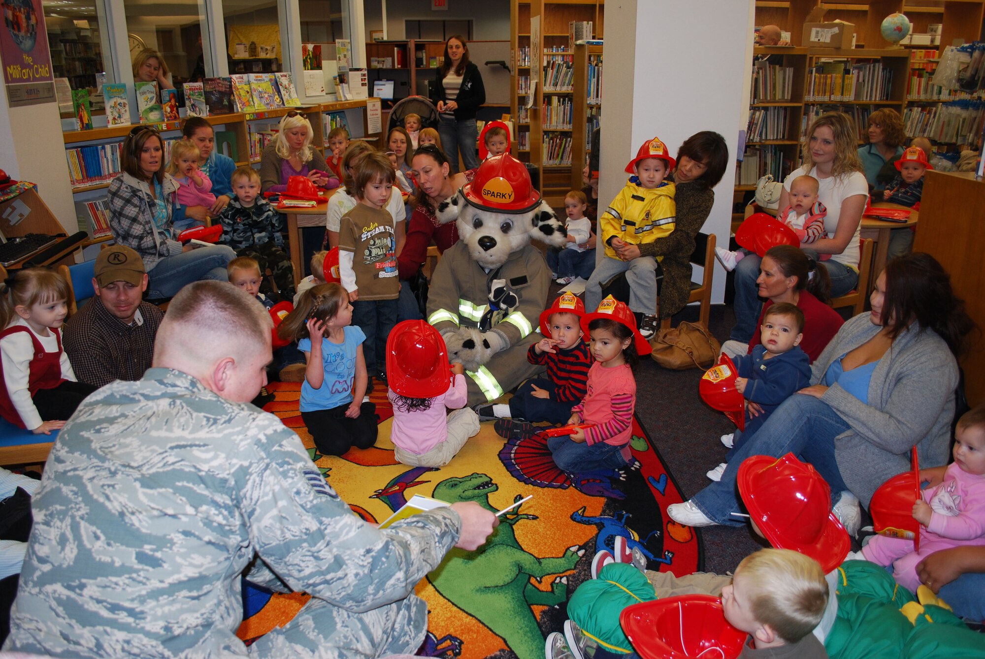 Staff Sgt. Shawn Flood, 341st Civil Engineer Squadron fire fighter, reads fire safety books to Sparky The Fire Dog and children at the base library Oct. 6. Sparky was the special guest during National Fire Prevent Week Oct. 4 to 9. This year's theme is "Stay Fire Smart! Don't Get Burned!"  (U.S. Air Force photo/Staff Sgt. Eydie Sakura)