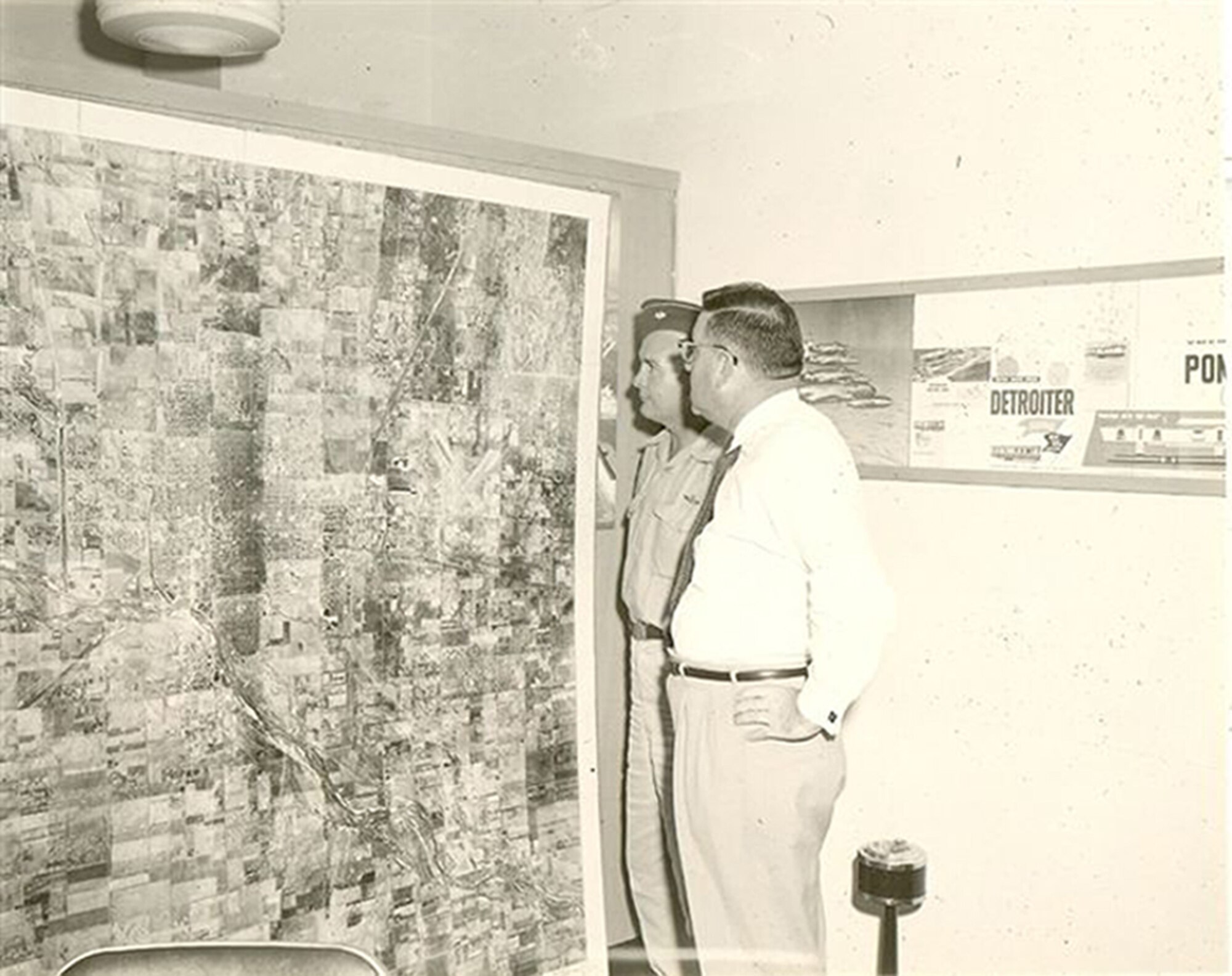 Lt. Col. Carl Boggs, 117th commander, showing one the squadron's aerial photos to a local businessman from the Hutchinson area.