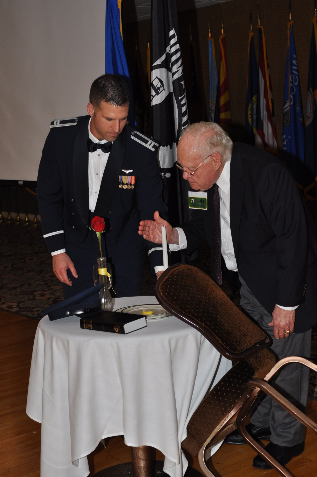 Mr. Frank Mullinax, 49th WWII P-38 pilot and former POW and Capt. Nick Graham, 49th Fighter Training Squadron, extinguish the candle on the POW/MIA table at the conclusion of the 49th FS Association banquet October 10 at the Columbus Club.  Mullinax was a former WWII POW spent nine months in captivity in Italy during 1943and 10 months evading after his escape from a moving train. (U.S. Air Force photo/Sonic Johnson). 