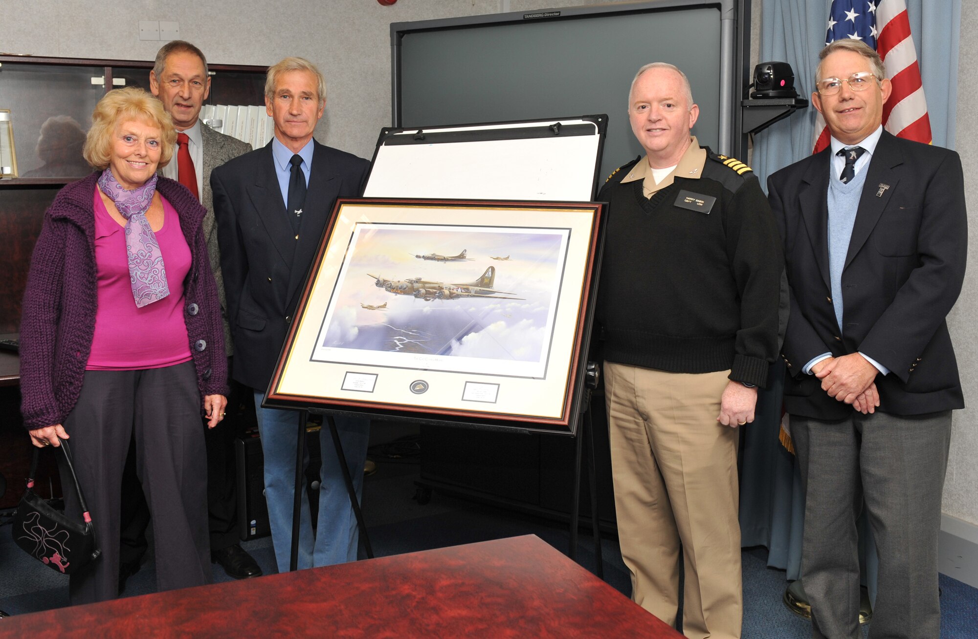 British aviation and military artist Mr. Keith Hill (2nd from left) stands with JAC Deputy Commander Capt. Henry J. "Harry" Babin as they unveil the artist's latest work "The Cat Comes Home. " Others in the photo include Mrs Jean Gell, Jim Gell (who was an infant when the plane crashed in his back yard in 1943), and Mr. Gell's brother Andrew (U.S. Air Force photo by Staff Sgt. Javier Cruz)