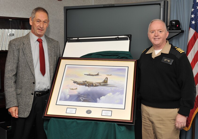 JIOCEUR Analytic Center Deputy Commander, Capt. Henry J. "Harry" Babin and noted British aviation and military artist Mr. Keith Hill unveil the artist's latest work "The Cat Comes Home" depicting a B17F of the 303rd Bomb Group.  "The Cat" was badly damaged and her crew parachuted to safety before the plane crashed in Bedfordshire, England.  (U.S. Air Force photo by Staff Sgt. Javier Cruz)