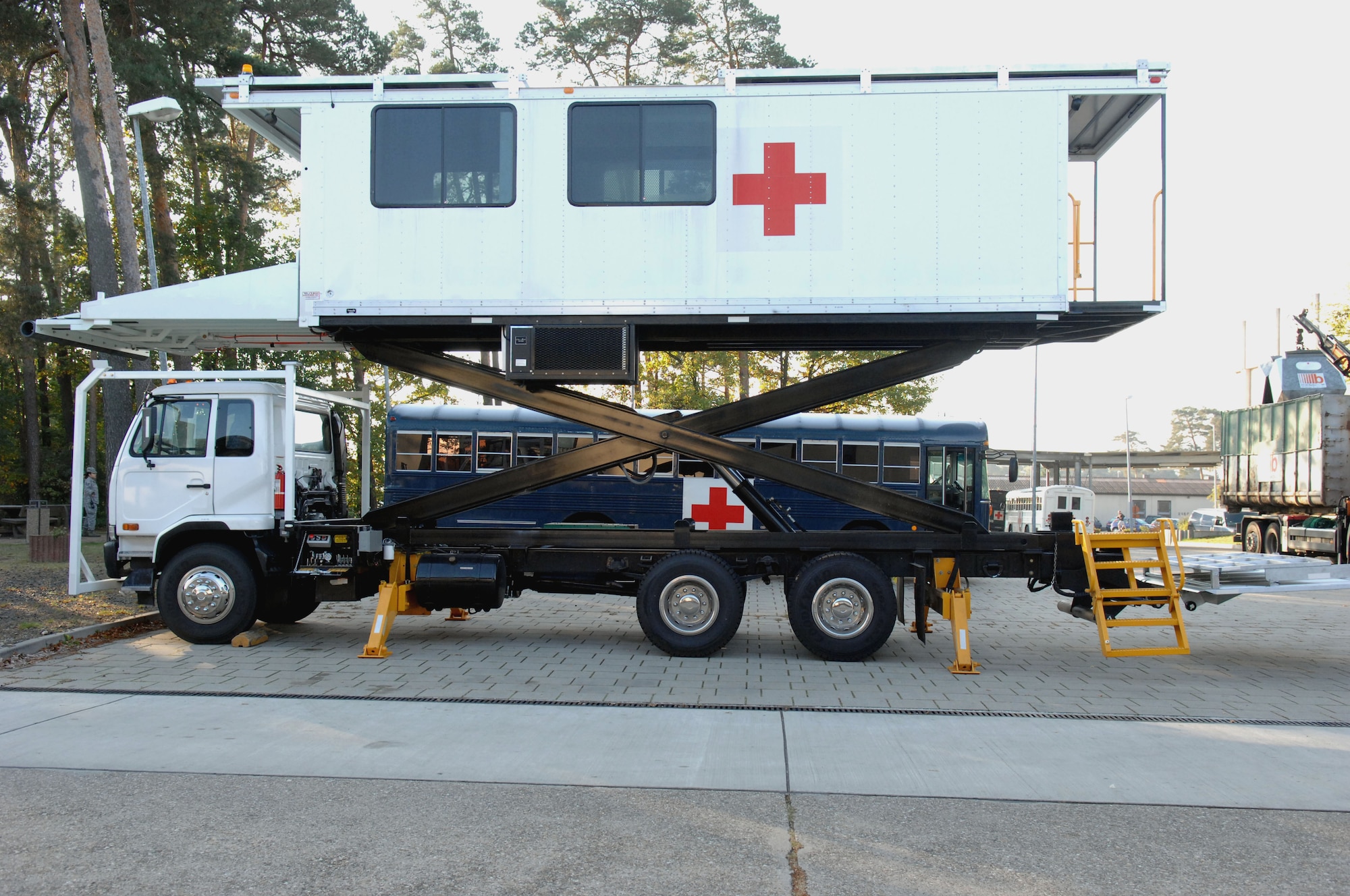 The high deck patient loading platform vehicle, or HDPLP, sits in a raised position to show the scissor-lift underneath the vehicle. The HDPLP was an Air Force idea to help give better care to wounded warriors. By taking a vehicle frame and adding modifications, the Air Force was able to modernize a standard vehicle for warrior care while allowing for base vehicle maintenance squadrons to sustain the required standards for operations, Ramstein Air Base, Germany. (U.S. Air Force photo by Airman 1st Class Brittany Perry)