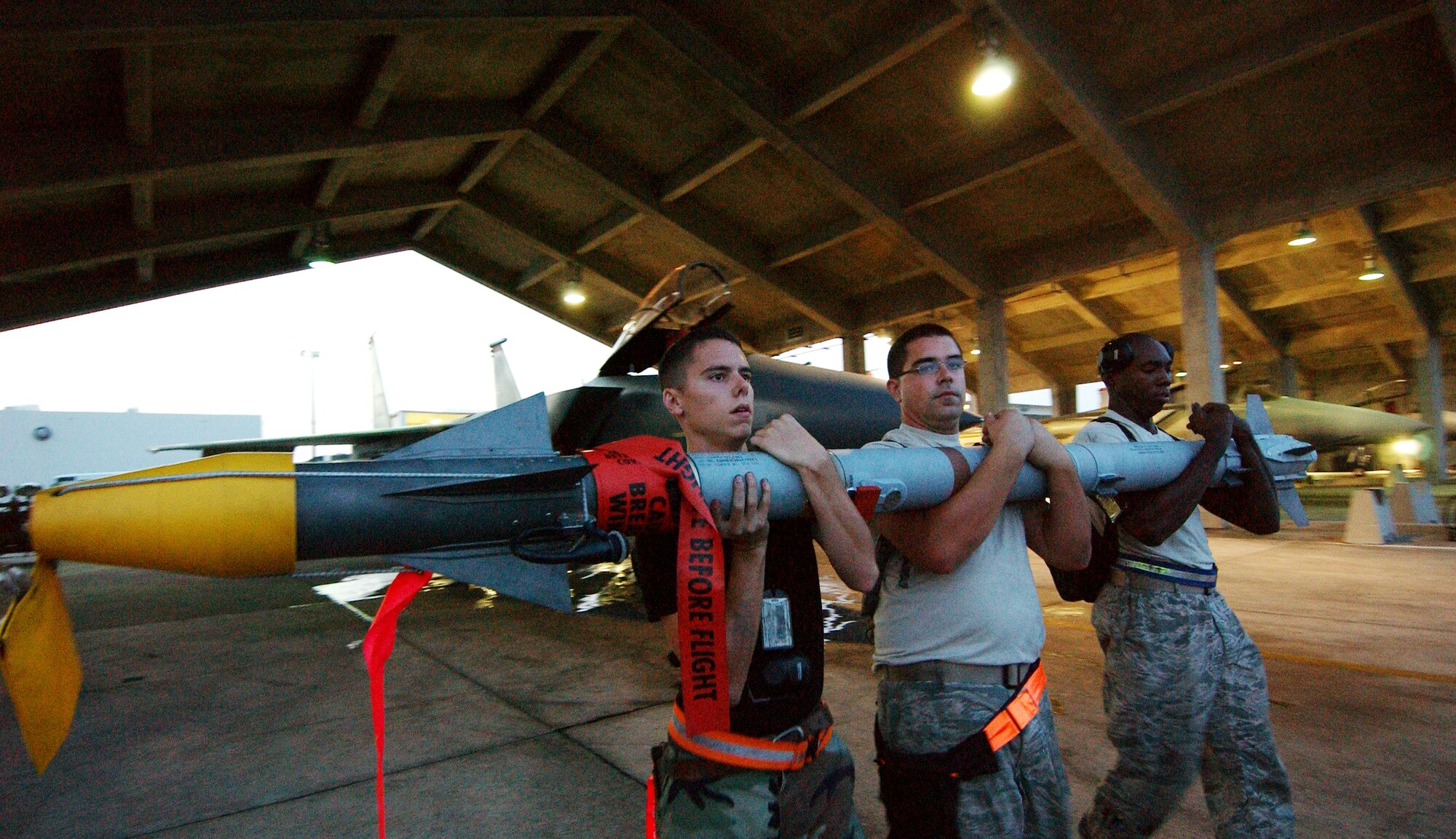Airman 1st Class Tyler Kennemer, Staff Sgt. Joseph Radowski, and Senior Airman Johnathan Gales from the 67th Aircraft Maintenance Unit configure an Aim-9 on a weapons trailer at Kadena Air Base, Japan Oct. 19 during Exercise Beverly High 10-01. The 18th Wing is participating in a Local Operational Readiness Exercise to test the readiness of Kadena Airmen Oct. 19-23.  
(U.S. Air Force photo/Tech. Sgt. Rey Ramon)  
                                                 
