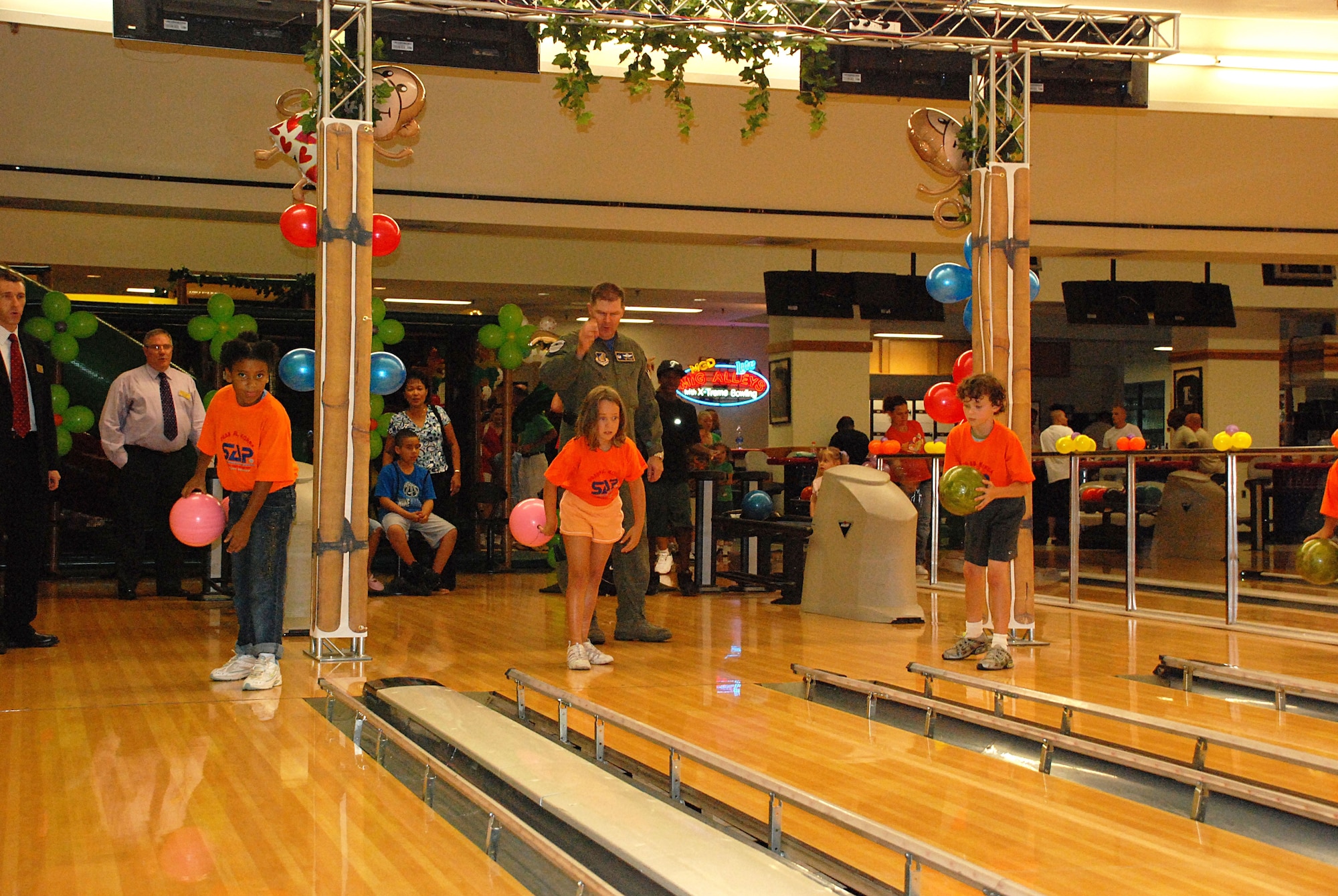 Col. Thomas Deale give children from the Osan School Age Program tips on throwing the ball at the grand opening of Osan's Family Entertainment Center at the Osan Bowling Alley.  As tour normalization continues in Korea service members and agencies on Osan AB, continue to work together to turn Osan into more of a a family-friendly environment. Colonel Deale is the 51st Fighter Wing commander. (U.S. Air Force photo/Jesse Diaz)