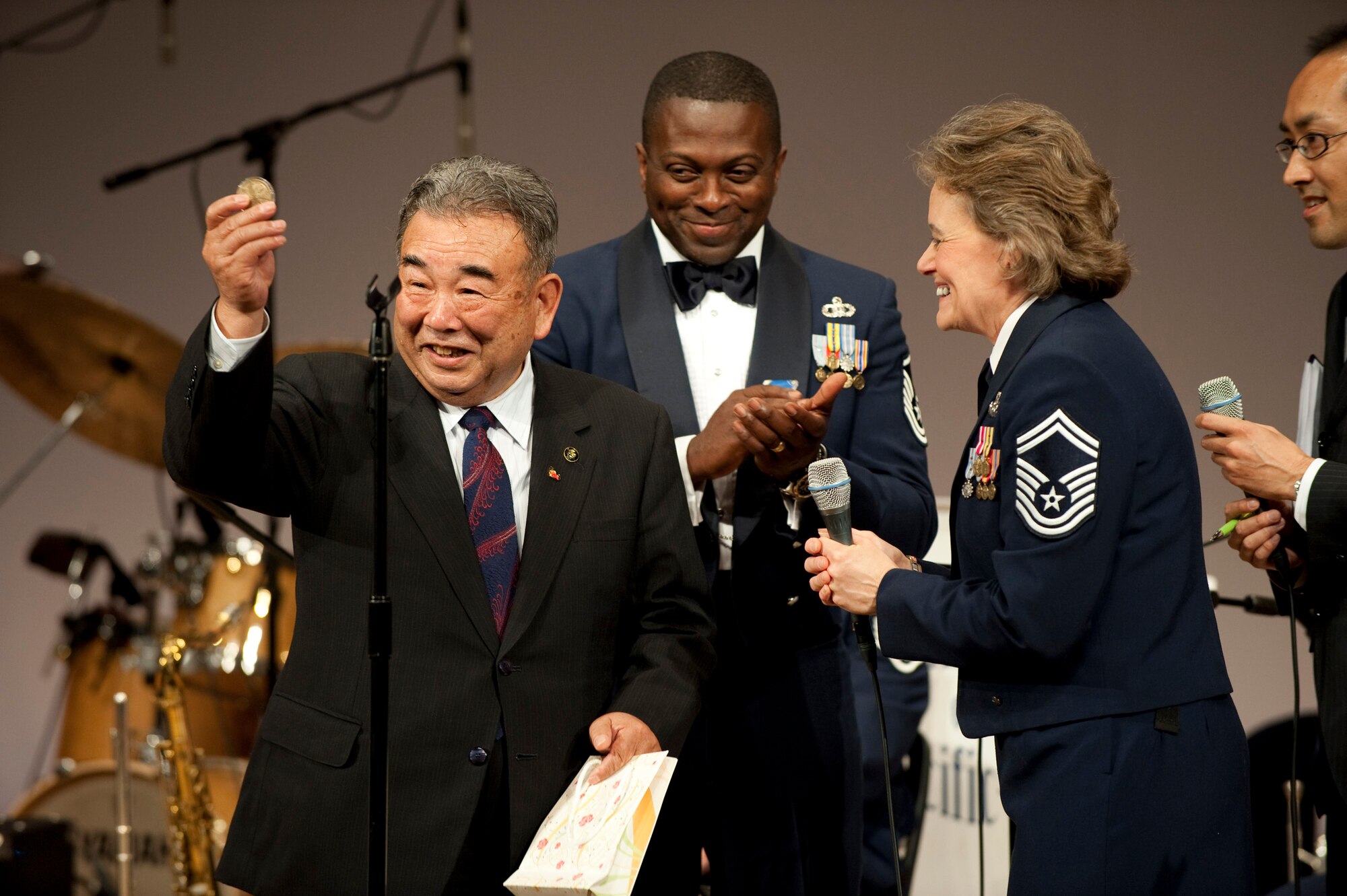 MISAWA AIR BASE, Japan -- Misawa Mayor Kazumasa Taneichi holds up a coin from the Greatlanders, Pacific Air Forces show band, at the Misawa International Center Oct. 17. Master Sgt. Katherine Cooper, band manager, presented the coin to Mayor Taneichi to thank him for his support and sponsorship for the band's performance that night. (U.S. Air Force photo/Staff Sgt. Samuel Morse)