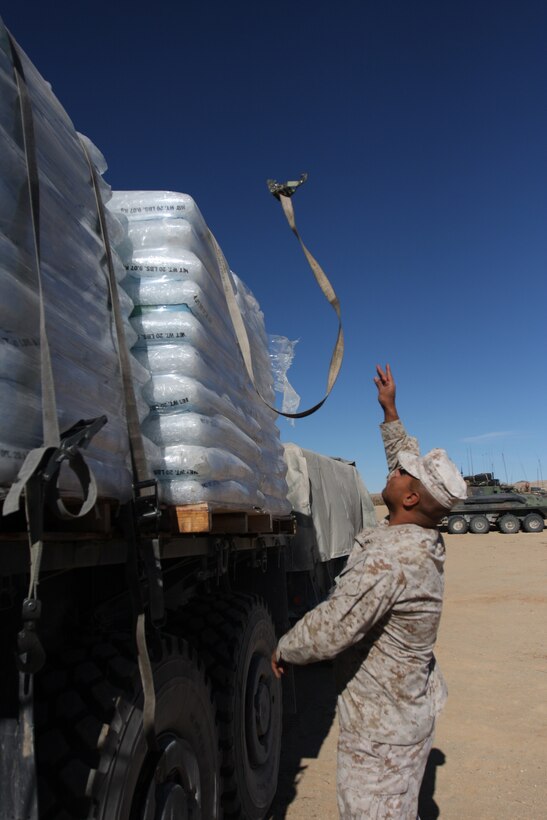 Lance Cpl. Salvador Portillo, a motor transpiration operator for Support Co., Combat Logistics Battalion 7, throws one of the straps holding down the shipment of ice to 1st Light Armored Reconnaissance Battalion at the Combat Center Twentynine Palms Oct. 21. In the hot months of the year ice is an important supply for the units out in the field.