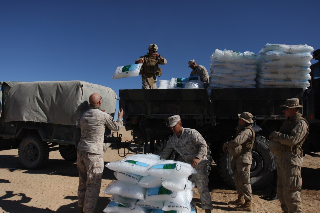 Lance Cpl. Salvador Portillo, Lance Cpl. Justin Harris, transportation operators for Support Co., Combat Logistics Battalion 7, and a working party from the 1st Light Armored Reconnaissance Battalion restack a tipped shipment of ice at the Combat Center Oct. 21.