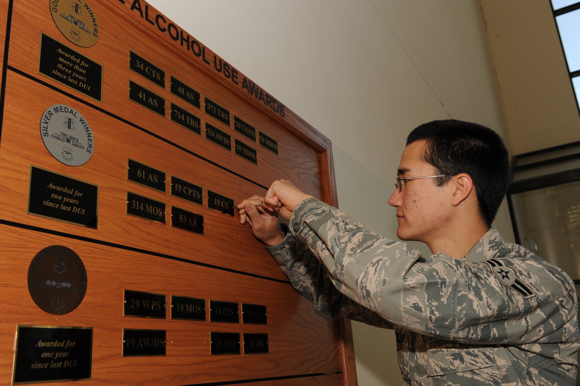 Airman 1st Class Scott McKillop, 19th Communications Squadron, promotes the 19 CS to the "Silver Medal Winners" bracket on the "Responsible Alcohol Use Awards" board at the base fitness center Oct. 20. The Silver Medal bracket marks units who have been DUI free for at least two years. (U.S. Air Force photo by Staff Sgt. Chad Chisholm)