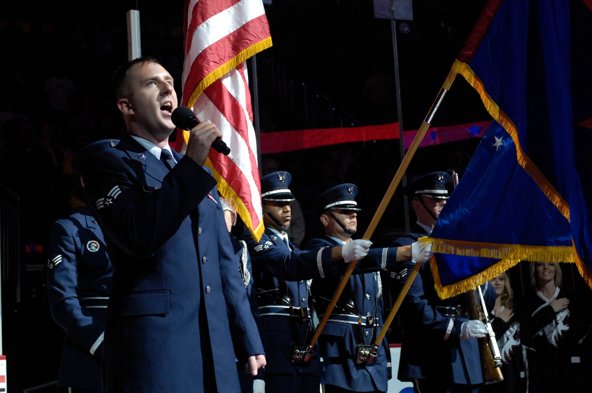 Senior Airman Robert Amirault, 308th Aircraft Maintenance Unit, sings the National Anthem while Luke Air Force Base Honor Guard members present the colors at the Jobing.Com Areana in Glendale, Arizona, Oct. 17, 2009. The events of that night are part of a bi-annual Phoenix Coyotes hockey team U.S. Armed Forces appreciation night.(U.S. Air Force Photo by Staff Sgt Jason Colbert)