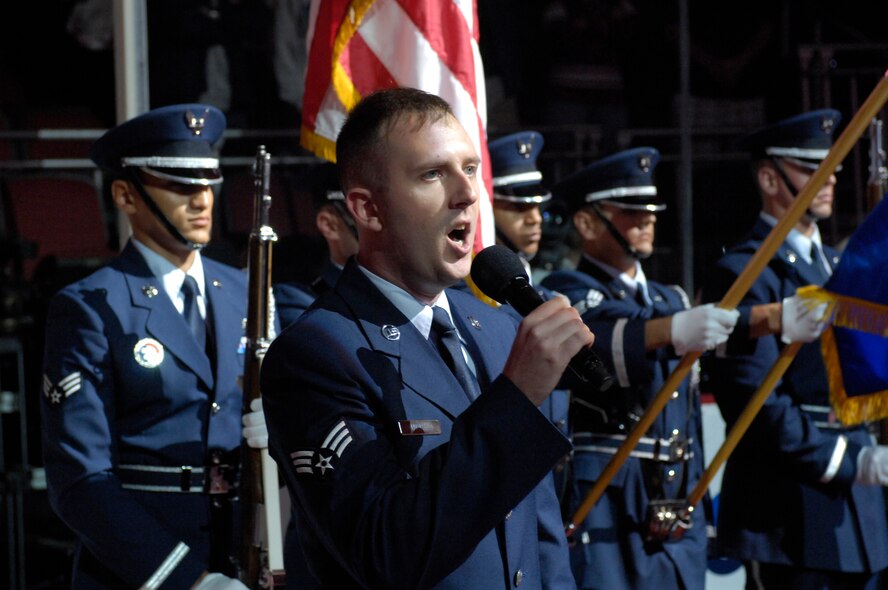 Senior Airman Robert Amirault, 308th Aircraft Maintenance Unit, sings the National Anthem while Luke Air Force Base Honor Guard members present the colors at the Jobing.Com Areana in Glendale, Arizona, Oct. 17, 2009. The events of that night are part of a bi-annual Phoenix Coyotes hockey team U.S. Armed Forces appreciation night. (U.S. Air Force Photo by Staff Sgt Jason Colbert)