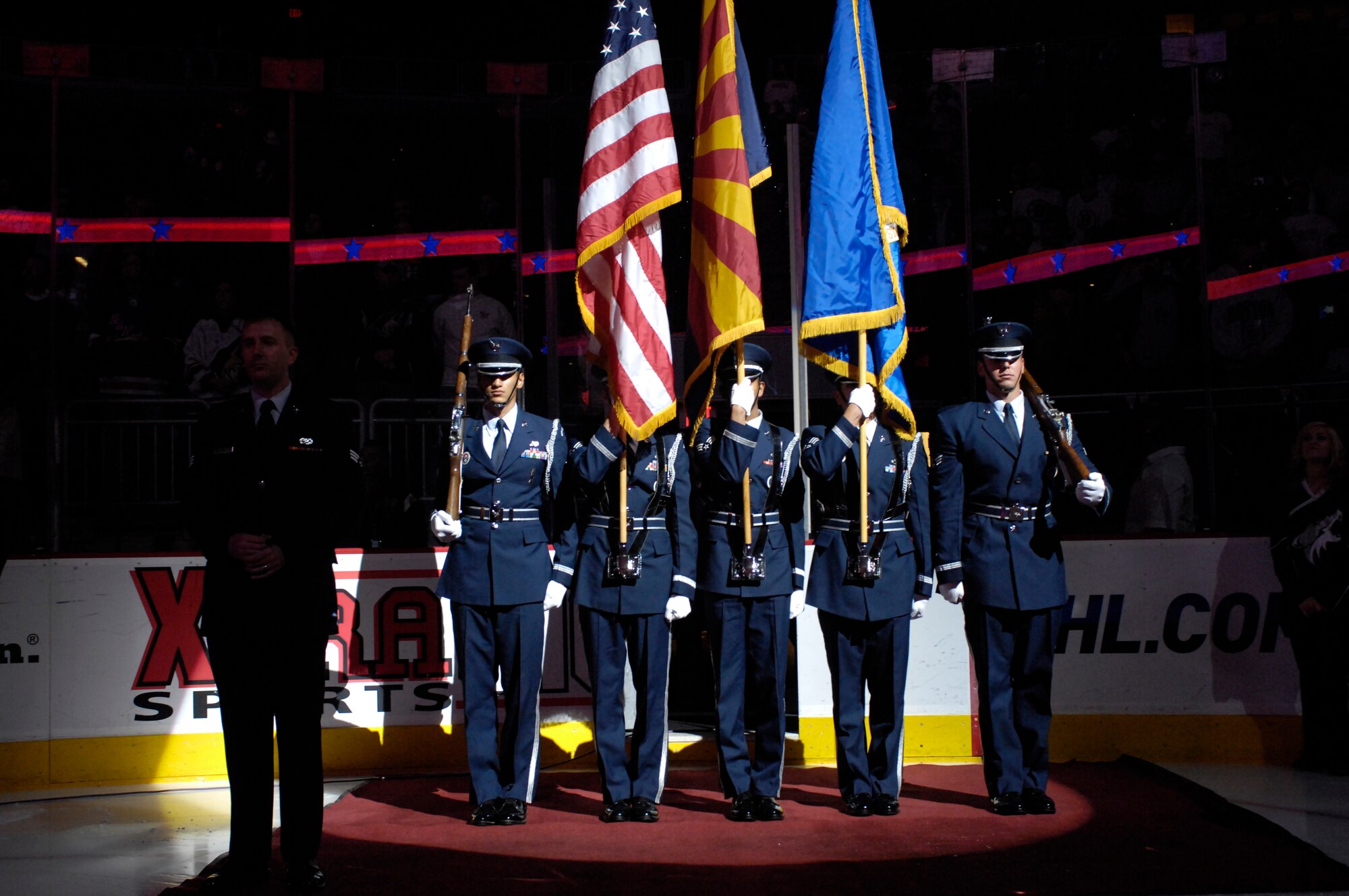 Luke Air Force Base Honor Guard members stand ready to present the colors while Senior Airman Robert Amirault, 308th Aircraft Maintenance Unit, prepares to sing the National Anthem at the Jobing.Com Areana in Glendale, Arizona, Oct. 17, 2009. The events of that night are part of a bi-annual Phoenix Coyotes hockey team U.S. Armed Forces appreciation night. (U.S. Air Force Photo by Staff Sgt Jason Colbert)