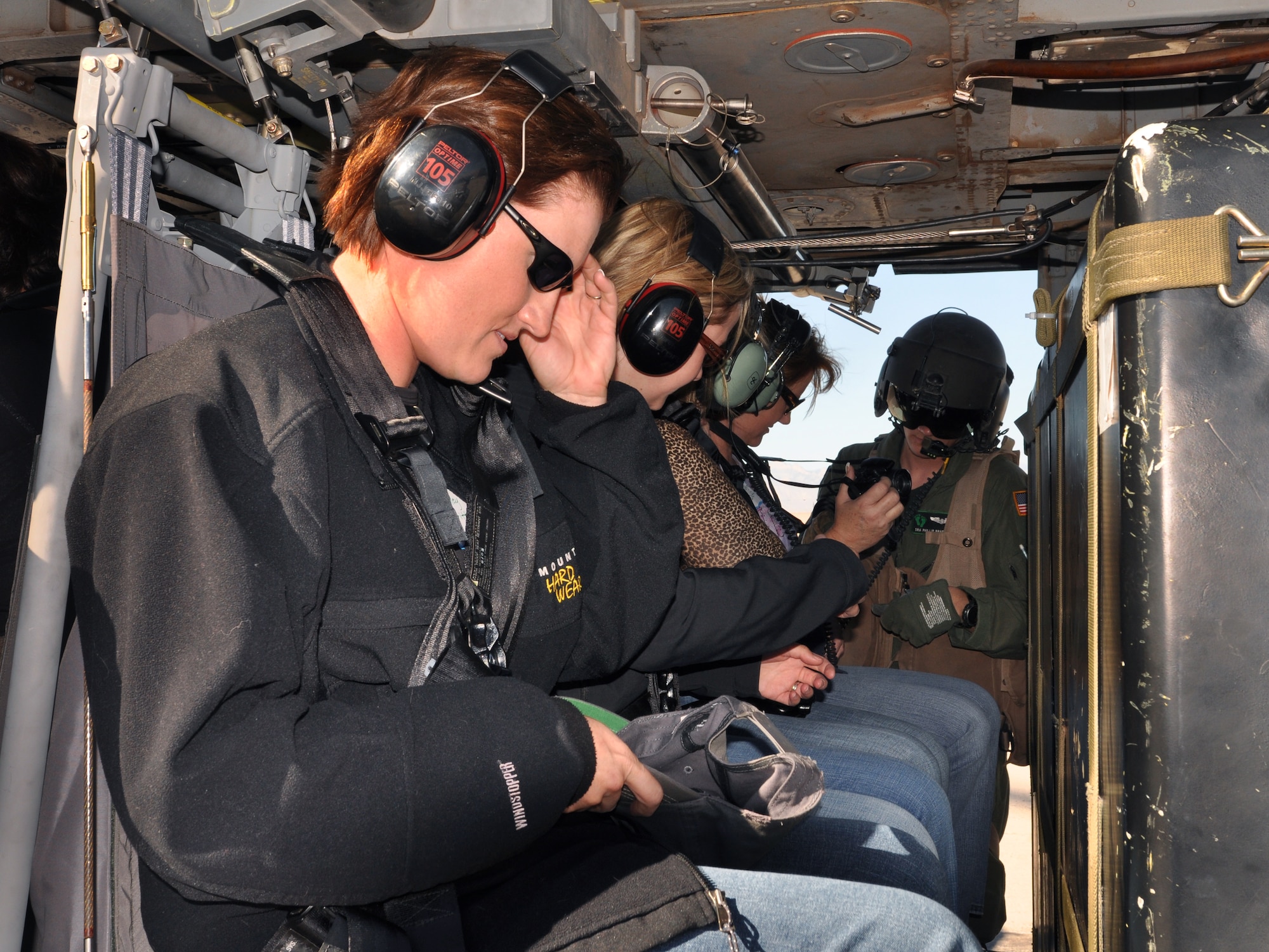NELLIS AIR FORCE BASE, Nev.-- Senior Airman Phillip Bradbury, 66th Rescue Squadron flight engineer, assists spouses with safety belts inside the HH-60G Pavehawk during the spouse orientation day Oct. 16, 2009.  Spouses of the 66th RQS, 58th RQS and 763rd Maintenance Squadron participated in orientation flights to become familiar with the training and the mission of the units.
(U.S Air Force Photo by Airman 1st Class Stephanie Rubi)