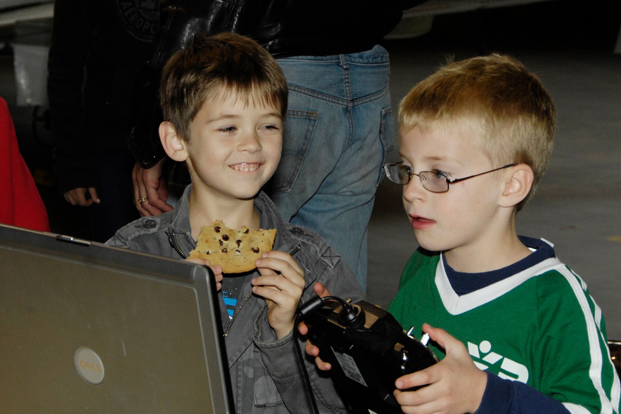 HANSCOM AIR FORCE BASE, Mass. – Aidan Mathey (left) enjoys a cookie while watching his friend Brian Thompson operate the controls of a radio airplane during the Aero Club Open House on Oct. 17. The event included free food and activities and information on flying for adults and children. (U.S. Air Force photo by Linda LaBonte Britt)