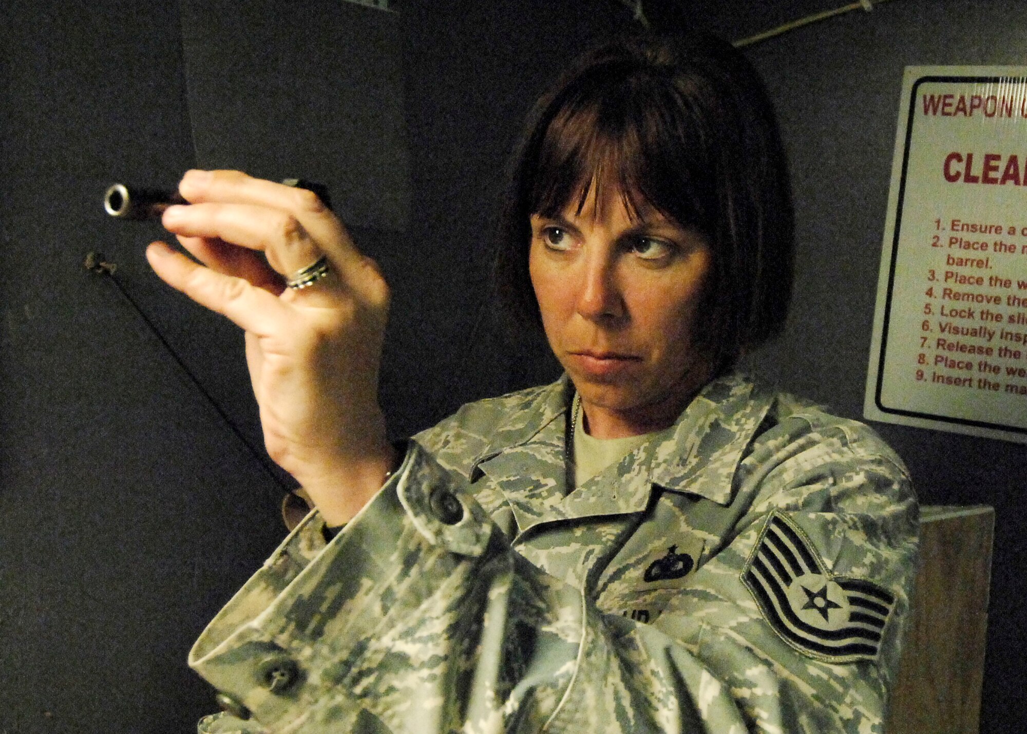 BAGRAM AIRFIELD, Afghanistan -- Tech. Sgt. Kimberley Grann, the noncommissioned officer-in-charge of physical security from the 455th Expeditionary Security Forces Squadron, inspects the cleanliness of the barrel of her M-9 pistol, Oct. 21, 2009.  Members of Bagram Airfield are advised to clean their weapons routinely.  This assures that member's weapons work properly and safely if needed.  Sergeant Grann is deployed from Pope Air Force Base, N.C., and hails from Madison, Wis.  (U.S. Air Force photo/Senior Airman Felicia Juenke)