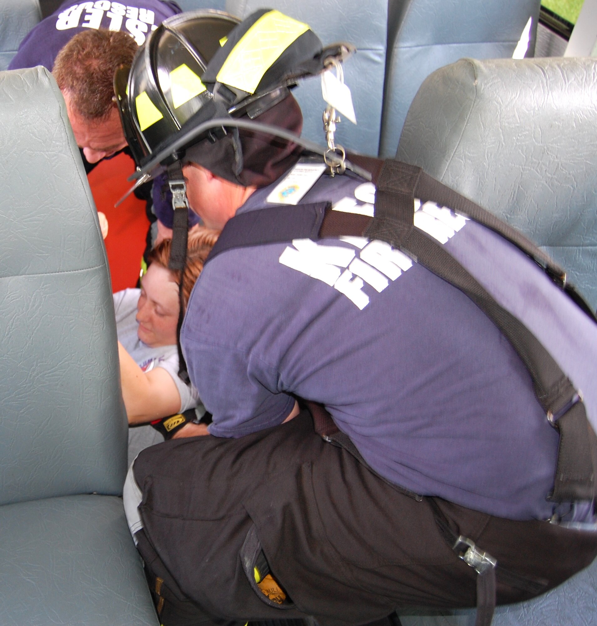 Keesler firefighters Rusty Bell, left, and Daniel Fish remove “victim” Airman 1st Class Jennifer Harter, 334th Training Squadron, from between seats on the bus at the accident site.  (U.S. Air Force photo by Steve Pivnick)