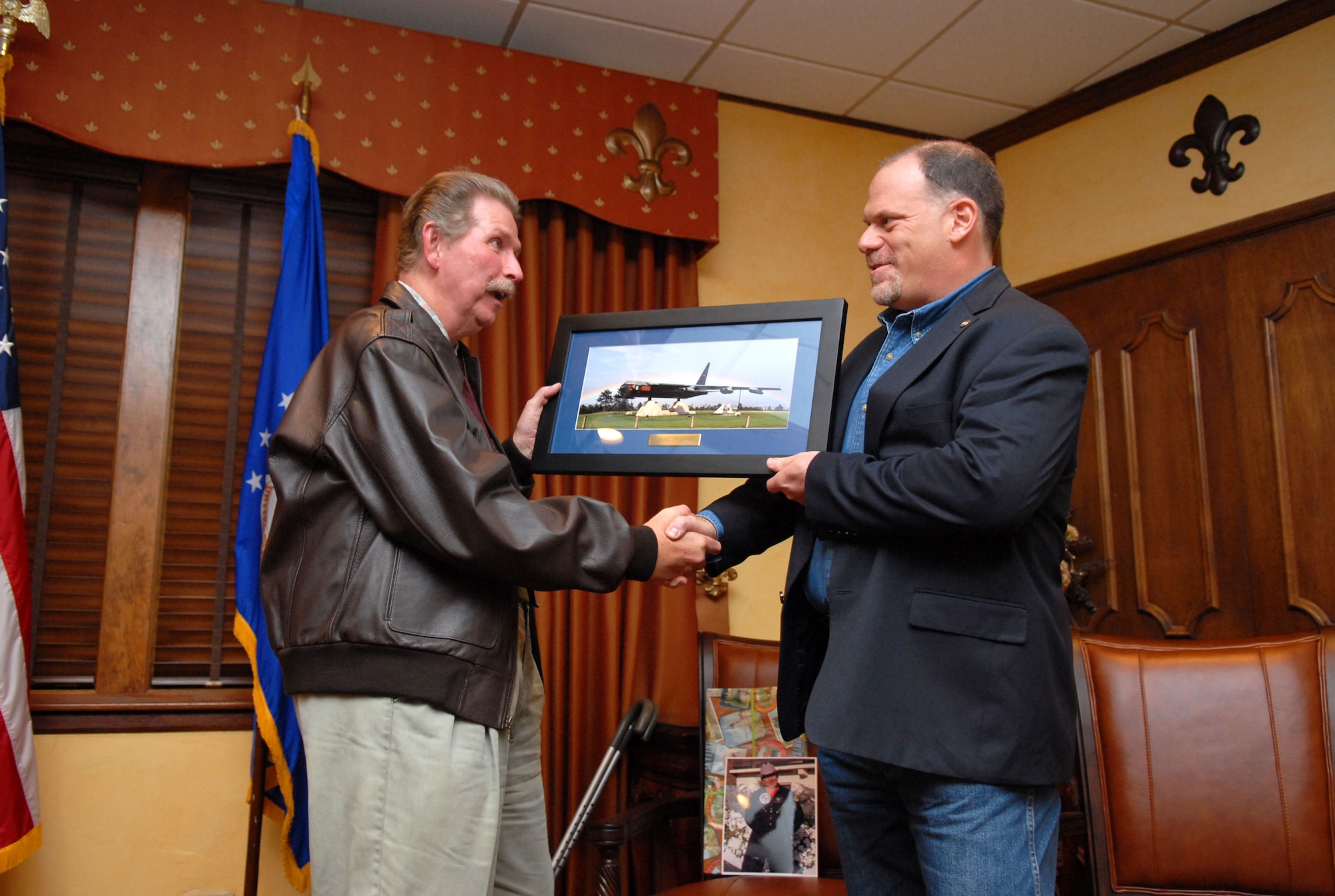 Mr. Harold “Buck” Rigg, founding curator of the 8th Air Force Museum, receives a photo of an aircraft from Master Sgt. (Ret.) Mike Kaplan, Air Force Academy contract photographer, during his retirement ceremony in the Barksdale Officers’ Club Oct. 14. The aircraft in the photo is Diamond Lil, an aircraft Mr. Rigg’s father flew two missions on in the Vietnam War. (U.S. Air Force photo by Ryan S. Ivacic) (RELEASED)