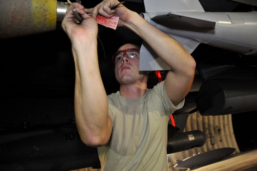 Senior Airman Derrick Pennington, a weapons load crew member, secures a Mark 82 onto an F-15 at Kunsan Air Base, Republic of Korea, Sept. 17. Airman Pennington is assigned to the 389th Expeditionary Fighter Squadron, deployed from Mountain Home Air Force Base, Idaho. Throughout the week, 389th EFS weapons loaders like Airman Pennington, along with other Airmen and pilots, trained with live munitions. (U.S. Air Force photo/Capt. Shannon Collins) 