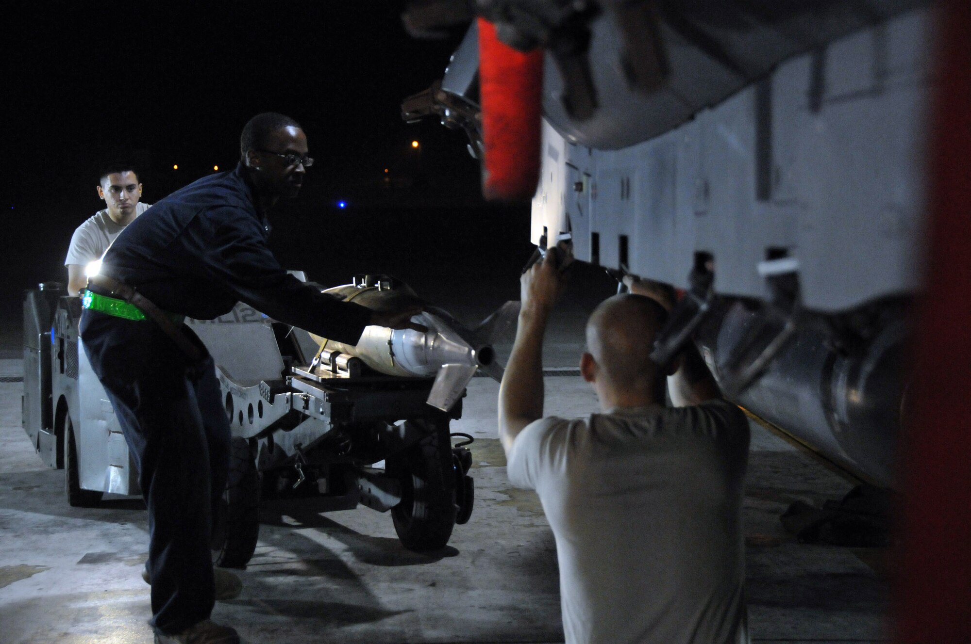 Airman 1st Class Ari Valdez, weapons load crew member, steers a jammer with a "live" Mark 82 as Staff Sgt. Dominique Battle, weapons load team chief, keeps it steady and Senior Airman Pennington, weapons load crew member, prepares to load it onto an F-15 at Kunsan Air Base, Republic of Korea, Sept. 17. Sergeant Battle and Airmen Pennington and Valdez are assigned to the 389th Expeditionary Fighter Squadron, deployed from Mountain Home Air Force Base, Idaho. Throughout the week, 389th EFS weapons loaders, along with other Airmen and pilots, trained with live munitions. (U.S. Air Force photo/Capt. Shannon Collins) 
