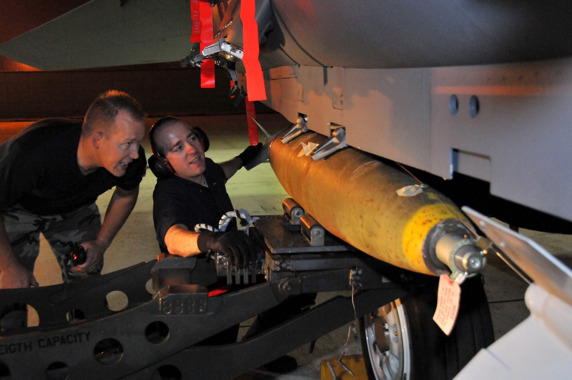Tech. Sgt. Jeremy Stradtmann, weapons expediter, looks on as Staff Sgt. Matthew Modgling, weapons load team chief, secures a Mark 82 onto an F-15 at Kunsan Air Base, Republic of Korea, Sept. 17. Sergeants Stradtmann and Modgling are assigned to the 389th Expeditionary Fighter Squadron, deployed from Mountain Home Air Force Base, Idaho. Throughout the week, 389th EFS weapons loaders, along with other Airmen and pilots, trained with live munitions. (U.S. Air Force photo/Capt. Shannon Collins) 