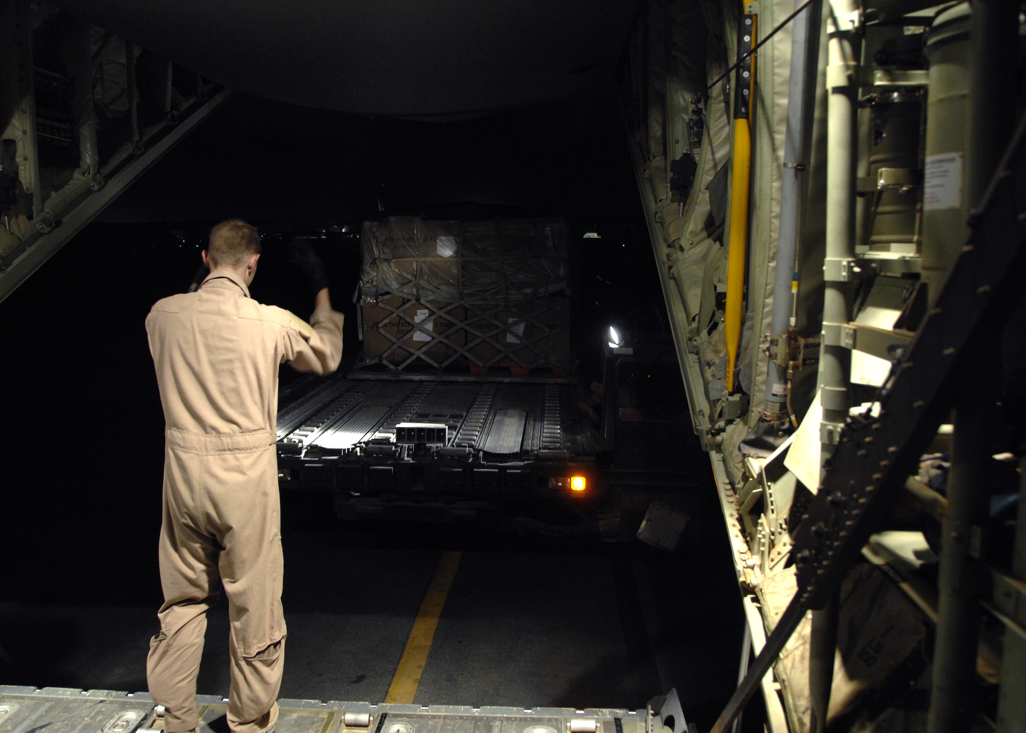 Senior Airman Scott McGuire directs a 60k Tunner to the back of a C-130J to upload cargo that will be transported down range, here, Oct. 17, 2009. The C-130 can accommodate a wide variety of oversized cargo, including everything from utility helicopters and six-wheeled armored vehicles to standard palletized cargo and military personnel. Airman McGuire is a C-130 loadmaster for the 772nd Expeditionary Airlift Squadron from Little Rock Air Force Base, Ark. (U.S. Air Force photo/Senior Airman Timothy Taylor)