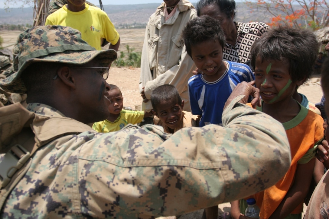 Second Lt. Jared Muse, a Marine with Company E, Battalion Landing Team 2/4, 11th Marine Expeditionary Unit, applies camouflage paint to a child from a nearby village here Oct. 22. The Marines trained with members of the Timor Leste Defense Force and the Australian Army during an exercise focused on promoting theater cooperation through civic action projects and military interaction.