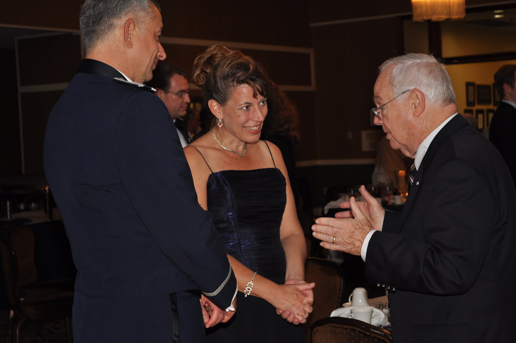 Colonel Roger Watkins, 14th Flying Training Wing Commander, and his wife Mrs. Leslie Watkins speak with Keith Ferris, Air Force aviation artist, at the 49th Fighter Squadron Association banquet. (U.S. Air Force photo/Sonic Johnson).