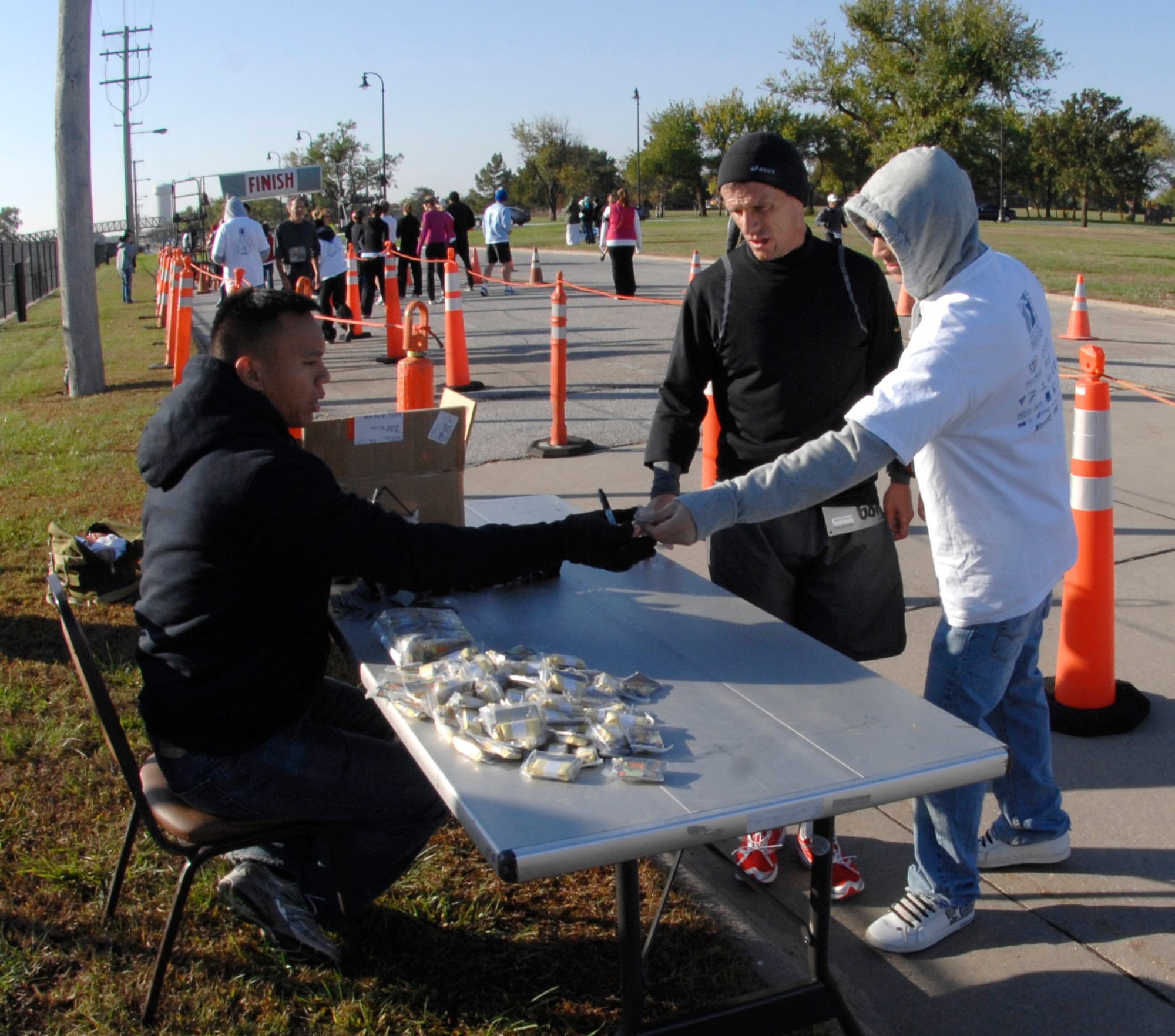 Staff Sgt. Stephen DeGuzman, 22nd Force Support Squadron, hands out prize medals to runners who reach the half-way point of the 2009 Heart of Wichita Marathon and Donovan Drive Marathon Relay, Oct. 18, 2009, at McConnell Air Force Base, Kan. The Heart of Wichita Marathon is a 26.2-mile race that starts in Derby, Kan., runs through McConnell and finishes in downtown Wichita, Kan. The Wichita Marathon is held annualy in conjunction with the Donovan Drive Half-Marathon, a 13.1-mile race that follows the same course but ends at McConnell.(U.S. Air Force photo/Senior Airman Laura Suttles)