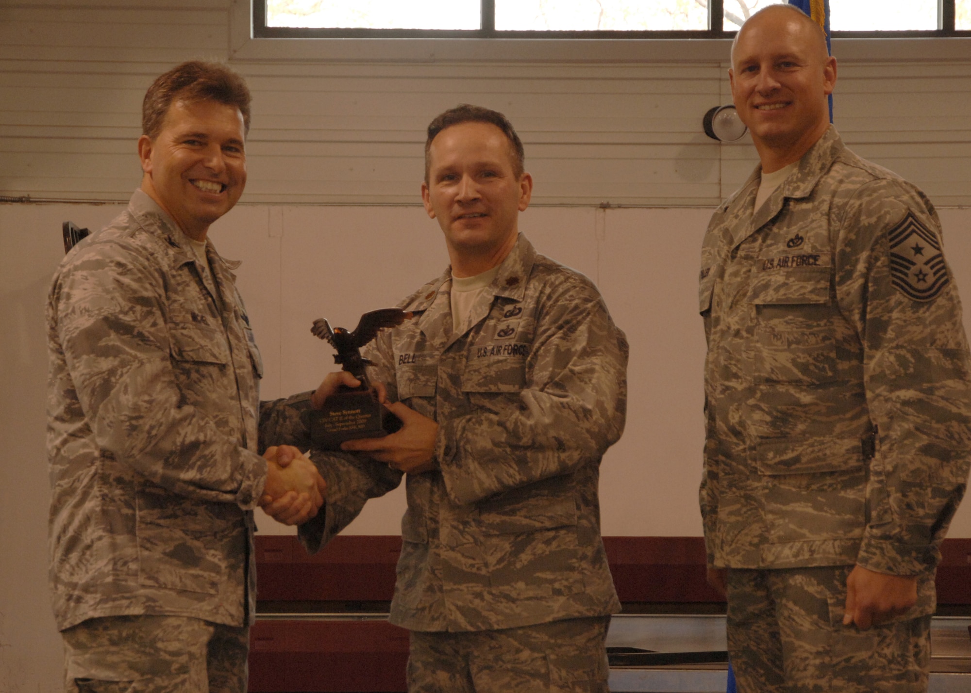 Col. John E. Michel, 319th Air Refueling Wing commander, hands the Category II Civilian of the Quarter award to Maj. Tracy Bell, 319th Comptroller Squadron commander, who is accepting the award for Steven E. Synnott, 319th CPTS, while Chief Master Sgt. Scott A. Fuller, 319th ARW command chief, looks on, Oct. 19 at the wing’s quarterly award ceremony. (U.S. Air Force photo by Senior Airman R. Michael Longoria)
