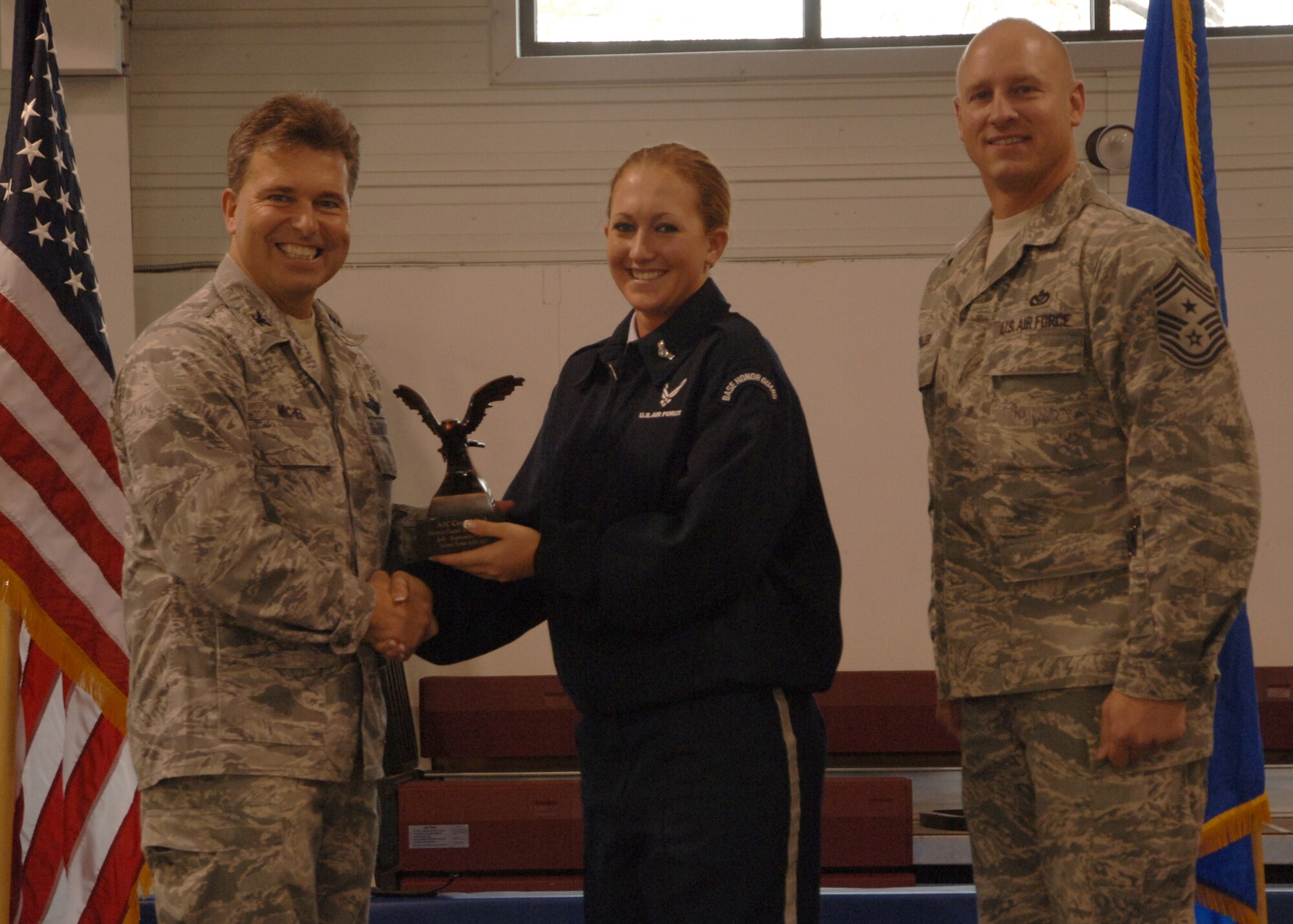 Col. John E. Michel, 319th Air Refueling Wing commander, hands the Honor Guard Member of the Quarter award to Airman 1st Class Crystal D. Dill, 319th Maintenance Group, while Chief Master Sgt. Scott A. Fuller, 319th ARW command chief, looks on, Oct. 19 at the wing’s quarterly award ceremony. (U.S. Air Force photo by Senior Airman R. Michael Longoria)