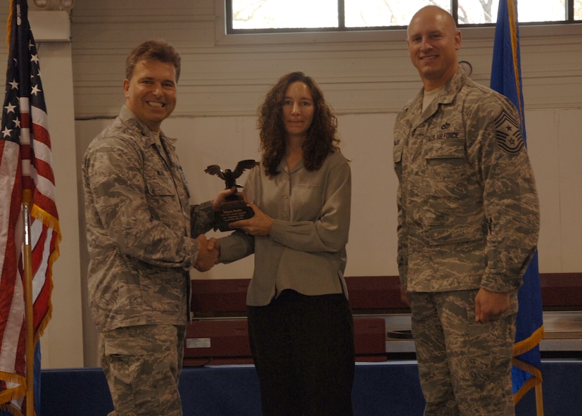 Col. John E. Michel, 319th Air Refueling Wing commander, hands the Category I Civilian of the Quarter award to Jolynne M. Findley, 319th Operations Support Squadron, while Chief Master Sgt. Scott A. Fuller, 319th ARW command chief, looks on, Oct. 19 at the wing’s quarterly award ceremony. (U.S. Air Force photo by Senior Airman R. Michael Longoria))