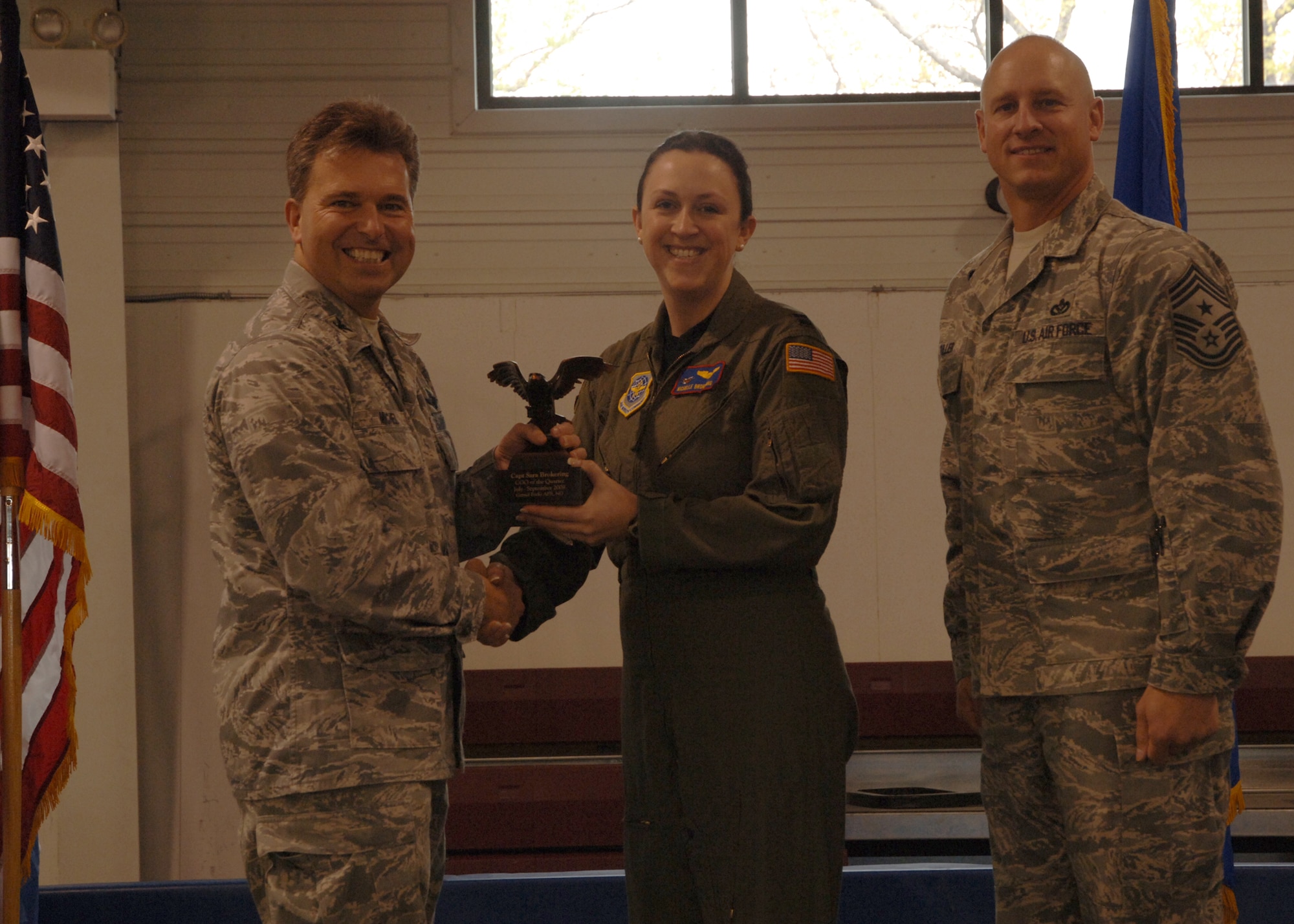 Col. John E. Michel, 319th Air Refueling Wing commander, hands the Company Grade Officer of the Quarter award to Capt. Sara N. Brokering, 319th Operations Support Squadron, while Chief Master Sgt. Scott A. Fuller, 319th ARW command chief, looks on, Oct. 19 at the wing’s quarterly award ceremony. (U.S. Air Force photo by Senior Airman R. Michael Longoria)