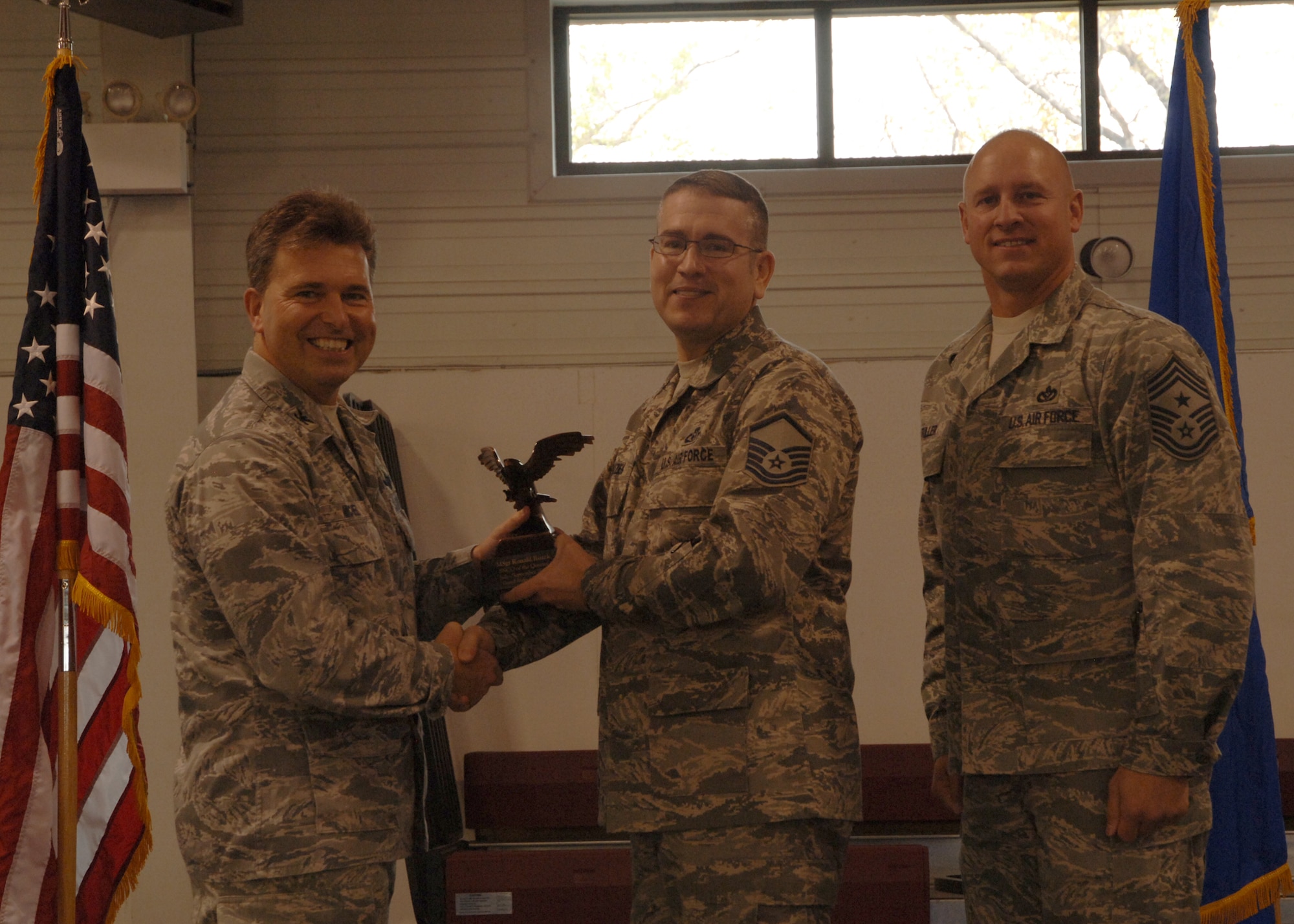 Col. John E. Michel, 319th Air Refueling Wing commander, hands the Senior NCO of the Quarter award to Master Sgt. Ronald J. Ruzek, 319th Operations Support Squadron, while Chief Master Sgt. Scott A. Fuller, 319th ARW command chief, looks on, Oct. 19 at the wing’s quarterly award ceremony. (U.S. Air Force photo by Senior Airman R. Michael Longoria)
