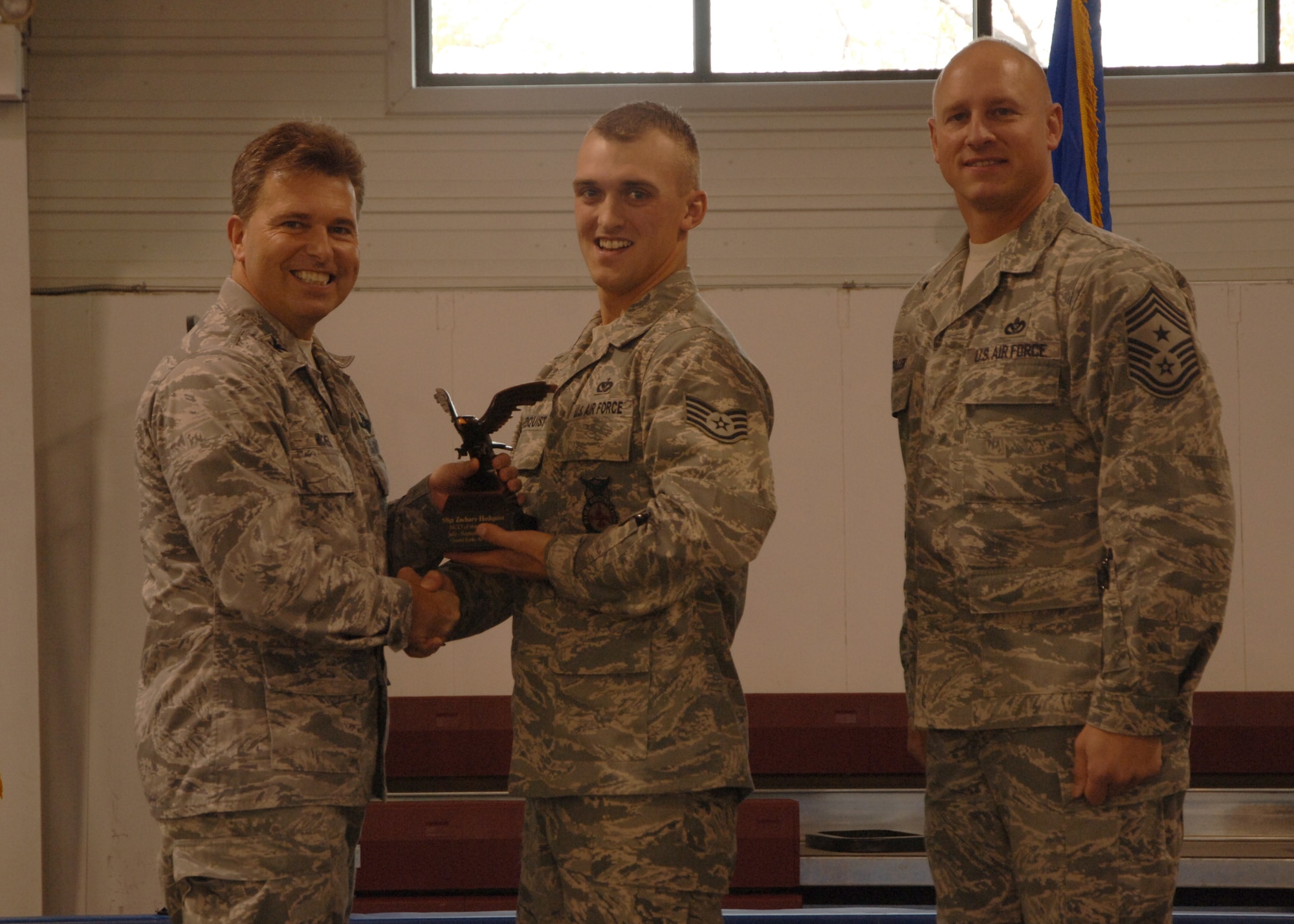 Col. John E. Michel, 319th Air Refueling Wing commander, hands the NCO of the Quarter award to Staff Sgt. Zachery J. Hedquist, 319th Civil Engineer Squadron, while Chief Master Sgt. Scott A. Fuller, 319th ARW command chief, looks on, Oct. 19 at the wing’s quarterly award ceremony. (U.S. Air Force photo by Senior Airman R. Michael Longoria)