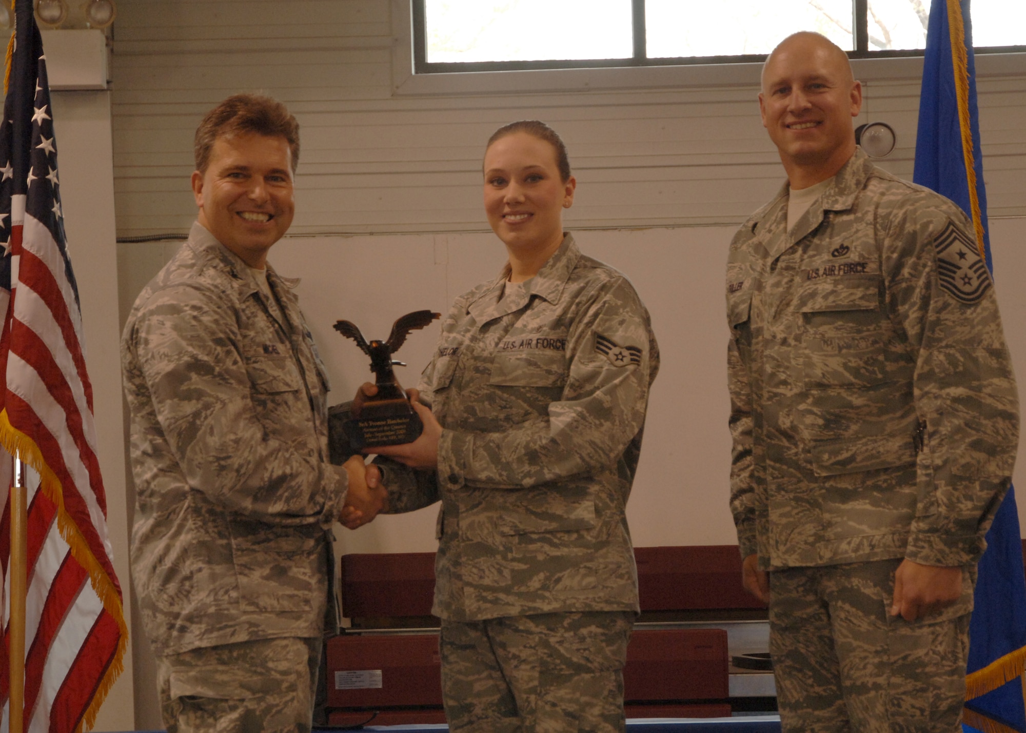 Col. John E. Michel, 319th Air Refueling Wing commander, hands the Airman of the Quarter award to Senior Airman Yvonne M. Batchelor, 319th Medical Operations Squadron, while Chief Master Sgt. Scott A. Fuller, 319th ARW command chief, looks on, Oct. 19 at the wing’s quarterly award ceremony. (U.S. Air Force photo by Senior Airman R. Michael Longoria)