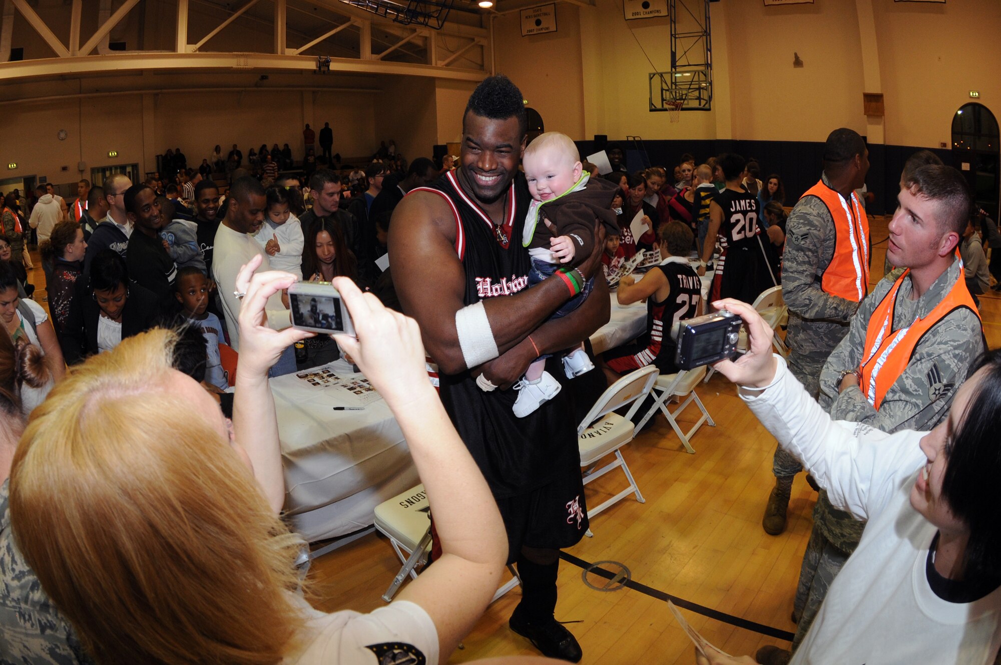 Justice, from the television show "American Gladiators", poses for pictures with military family members during the Hollywood Knights USO Tour Oct. 20, 2009 at the Dragon Fitness Center on Aviano Air Base, Italy. The Hollywood Knights celebrity basketball team competed in a game against 31st Fighter Wing leadership and members of the base's varsity basketball team. The home team beat the Hollywood Knights 82-76. The celebrities signed autographs and took photos with fans during halftime and after the game. The Hollywood Knights consists of television, motion picture and musical recording stars. (U.S. Air Force photo/ Staff Sgt. Patrick Dixon)