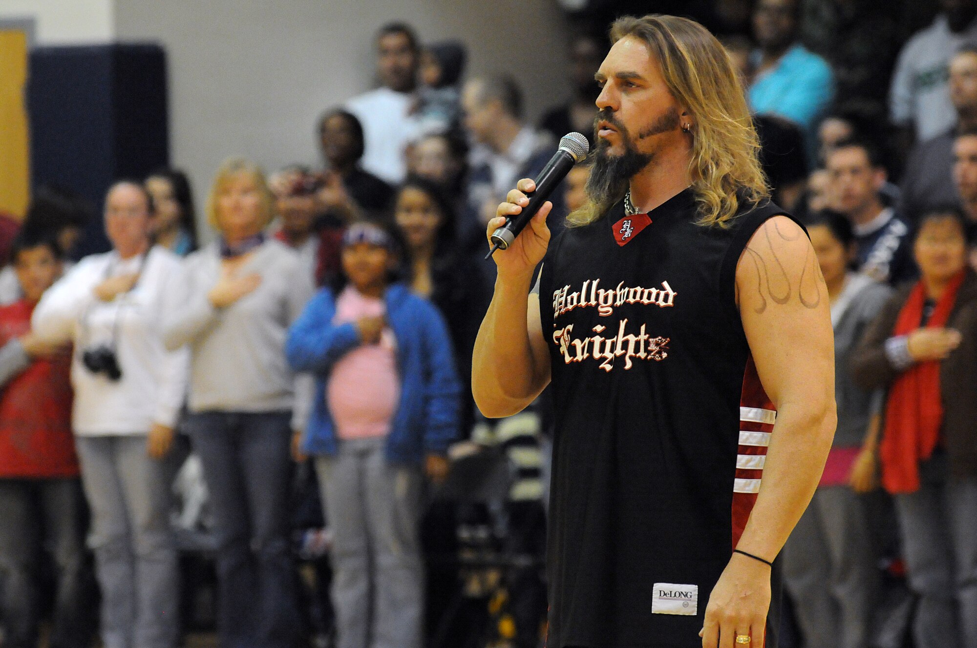 Wolf, from the television show "American Gladiators", sings the U.S. National Anthem before a basketball game during the Hollywood Knights USO Tour Oct. 20, 2009 at the Dragon Fitness Center on Aviano Air Base, Italy. The Hollywood Knights celebrity basketball team competed in a game against 31st Fighter Wing leadership and members of the base's varsity basketball team. The home team beat the Hollywood Nights 82-76. The celebrities signed autographs and took photos with fans during halftime and after the game. The Hollywood Knights consists of television, motion picture and musical recording stars. (U.S. Air Force photo/ Staff Sgt. Patrick Dixon)