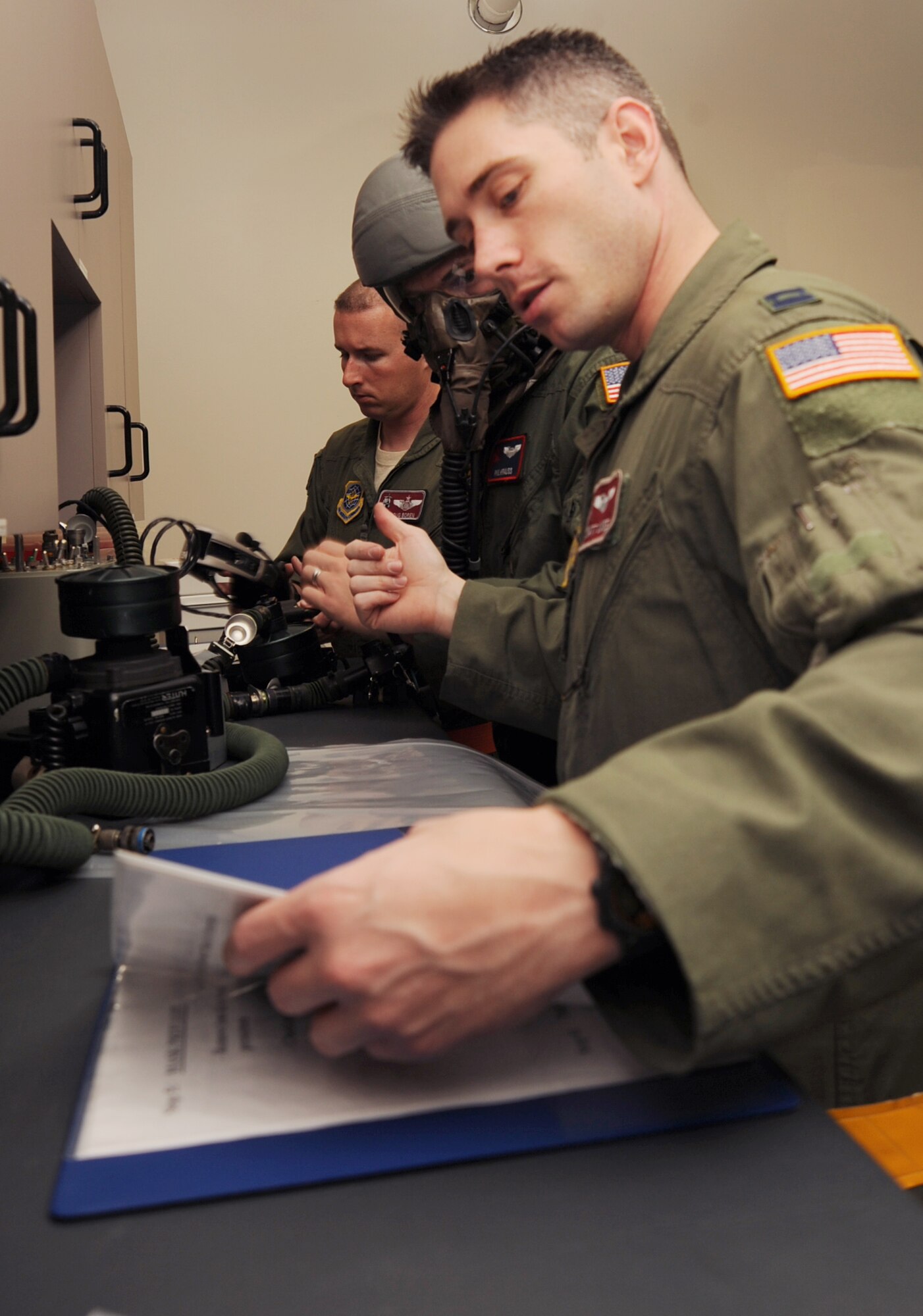 Capt. Matthew Swee, right, and Staff Sgt. Doug Boren, left, 384th Air Refueling Squadron aircrew members, review a pre-flight procedures manual, Oct. 15, 2009, as 1st Lt. Phil Krauss, 350th Air Refueling Squadron, tests an Aircrew Eye and Respiratory Protection System mask to ensure it is in working order. The aircrew ran through pre-flight procedure steps during Air Mobility Command’s first no-notice Nuclear Operational Readiness Inspection held at McConnell Air Force Base, Kan., Oct. 14 to 16. (U.S. Air Force Photo/Airman 1st Class Ruiz)