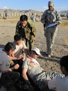 Staff Sgt. Allison Williams evaluates a team of 203rd Corps Afghan National Army medics as they provide combat care for a simulated injured soldier during the Inaugural ANA Combat Medic Challenge at Forward Operating Base Thunder, Afghanistan, Oct. 12. Forty-six select soldiers of the Afghan National Army sergeant vied for the best medic title in the competition that tested their physical fitness, marksmanship, combat lifesaver and medical evacuation assistance skills Oct. 10-14. The objective of the competition for the ANA medics was to hone combat lifesaver skills, build camaraderie, and inspire improvement through the spirit of competition. Sergeant Williams is deployed from the 1st Medical Group at Langley Air Force Base, Va., and her hometown is Princeton, N.C. She also applied the makeup on the soldiers to make the simulated wounds appear as realistic as possible for the competition, and seeing the surprised looks on the medics’ faces as they approached the “patients.” (U.S. Air Force photo/Tech. Sgt. Jennifer Lindsey)