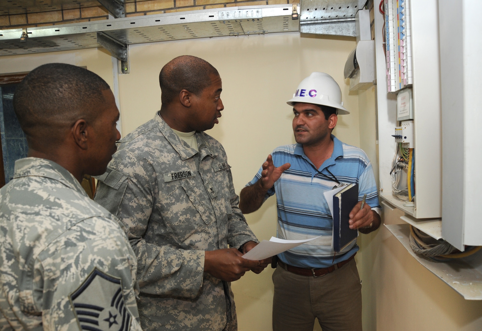 BAGHDAD -- Air Force Master Sgt. Tommy Robinson (left) and Navy Petty Officer 2nd Class Jack Frierson (center), joint area support group department of public works Team 2 noncommissioned officers, discuss an electrical panel with the Iraqi contractor who installed it during a construction project in the International Zone Oct. 18, 2009. The NCOs are responsible for ensuring contractors follow contract agreements, safety rules and national electric codes. Sergeant Robinson is deployed from Luke Air Force Base, Ariz., and hails from Graceville, Fla. Petty Officer Frierson is deployed from Norfolk Naval Air Station, Va., and hails from Kingtree, S.C.  (U.S. Air Force photo/Tech. Sgt. Johnny L. Saldivar)