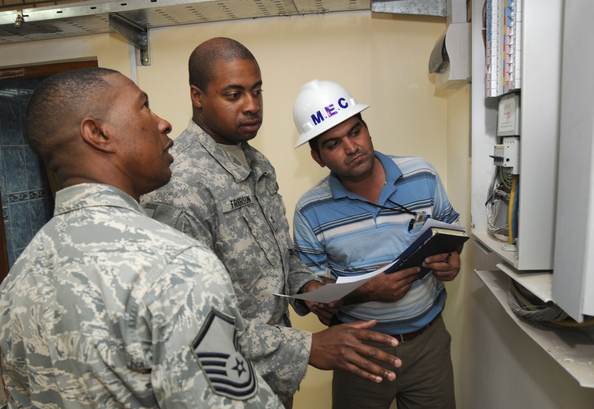 BAGHDAD -- Air Force Master Sgt. Tommy Robinson (left) and Navy Petty Officer 2nd Class Jack Frierson (center), joint area support group department of public works Team 2 noncommissioned officers, inspect an electrical panel installed by Iraqi contractors during a renovation project in the International Zone Oct. 18, 2009. The NCOs are responsible for ensuring Iraqi contractors awarded construction projects follow contract agreements, safety rules and national electric codes. Sergeant Robinson is deployed from Luke Air Force Base, Ariz., and hails from Graceville, Fla. Petty Officer Frierson is deployed from Norfolk Naval Air Station, Va., and hails from Kingtree, S.C.  (U.S. Air Force photo/Tech. Sgt. Johnny L. Saldivar)