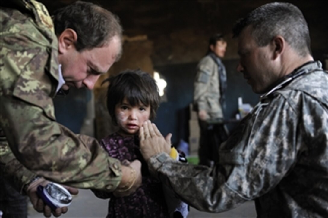 U.S. and Italian medical personnel apply lotion to an Afghan child's face and hands during a cooperative medical engagement near Camp Stone, Afghanistan, on Oct. 7, 2009.  More than 900 people received treatment during the three-day event.  