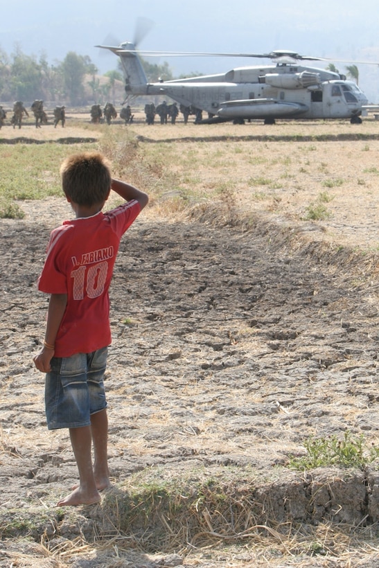 A child from a nearby village watches as Marines from Company E, Battalion Landing Team 2/4, board a CH-53E Sea Stallion helicopter here Oct. 22. The 11th Marine Expeditionary Unit members conducted jungle training with the Timor Leste Defense Force and Australian soldiers attached to the International Stabilization Force during an exercise there.