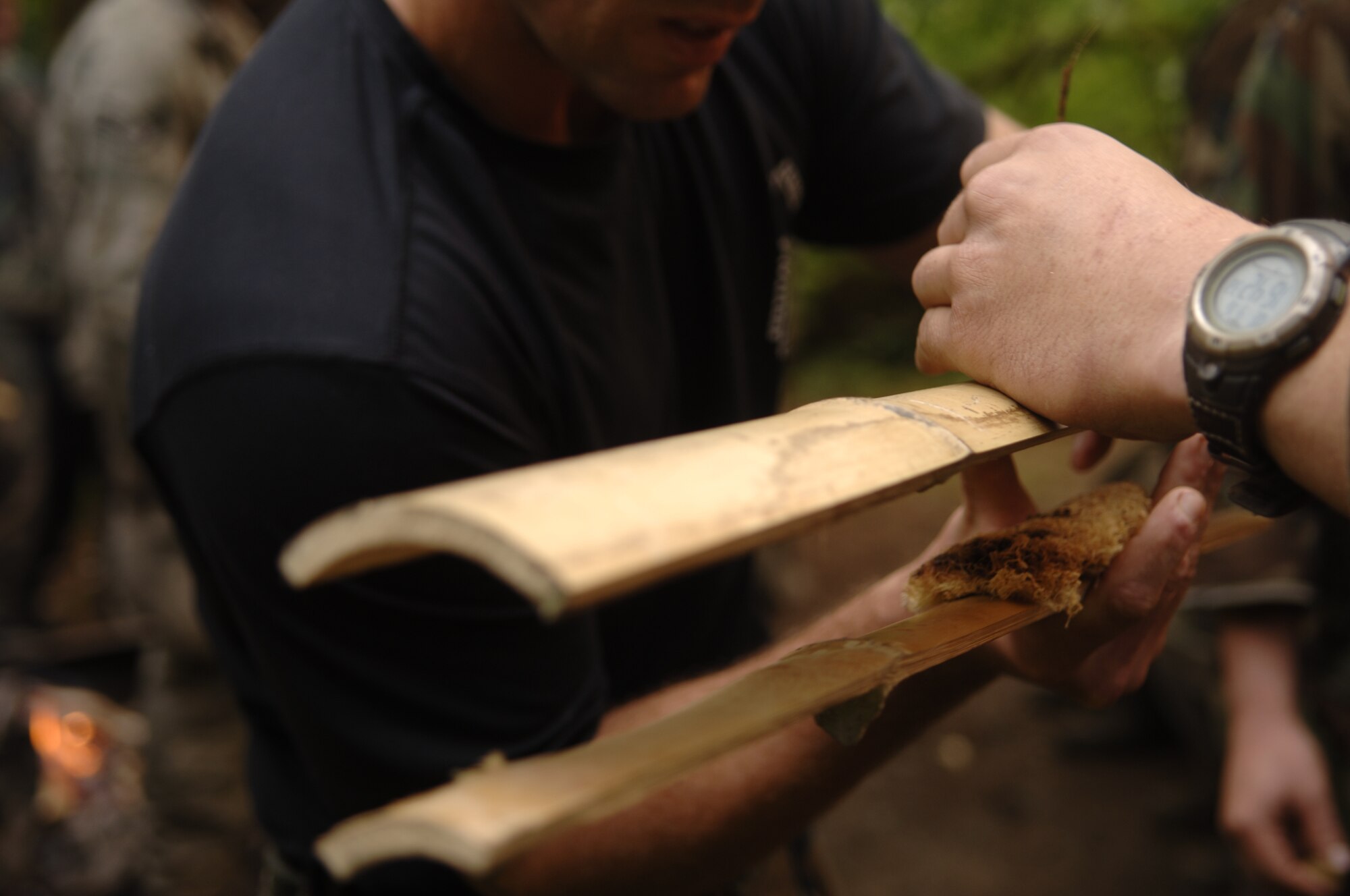 A SERE student places an ember on tinder in the Olympic National Forest’s rainforest. Students learned various fire starting techniques, including using bamboo, as making fire in such wet conditions proved challenging for many students over this phase of training.