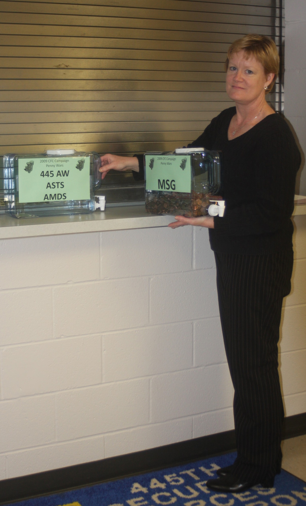 WRIGHT-PATTERSON AIR FORCE BASE, Ohio - Oct. 22 marked the kick off for the penny wars at the 445th Airlift Wing to raise money for the 2009 Combined Federal Campaign. Tech. Sgt. Linda Thrasher, 87th Aerial Port Squadron, shown here taking the penny jars to be counted, along with Tech. Sgt. Joan Weldon, 445th Mission Support Flight, are both CFC campaign chairmen for the wing. The wing will also have a chili cook-off Oct. 27 to raise money for the CFC.  Tickets can be bought in advance through your unit representative or at the door. (U. S. Air Force photo/Stacy Vaughn)

