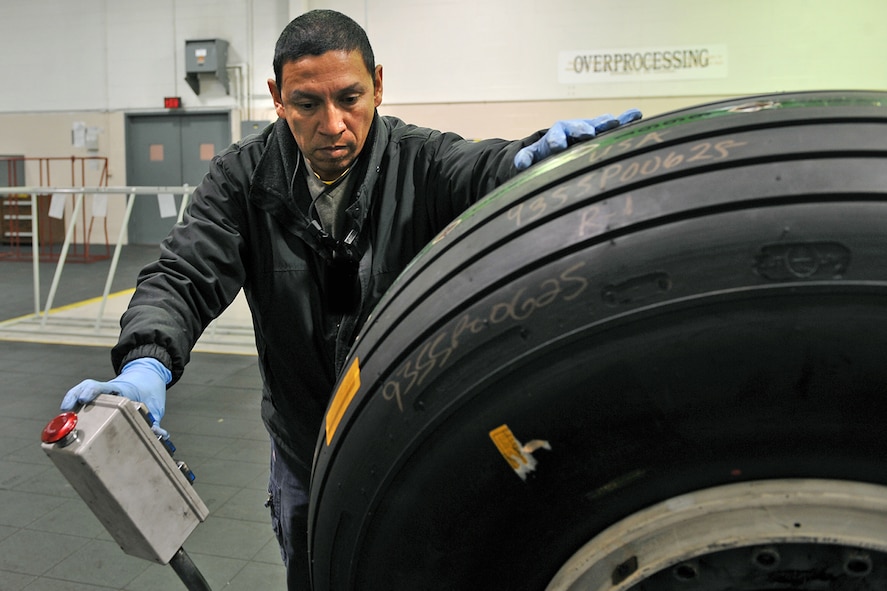 OFFUTT AIR FORCE BASE, Neb. - Greg Sanchez, an aircraft mechanic in the 55th Maintenance Squadron's isochronal phase inspection dock here, loads a tire on a universal wheel build up machine to separate the rim from the tire in the wheel and tire shop Oct. 15. In addition to working in the ISO dock in the Bennie Davis Maintenance Facility, the approximately 40 aircraft mechanics assigned also man the wheel and tire back shop when necessary. Each year, they process about 400 tires for the C-135 variants and E-4B aircraft here. Air Force photo by Charles Haymond 
